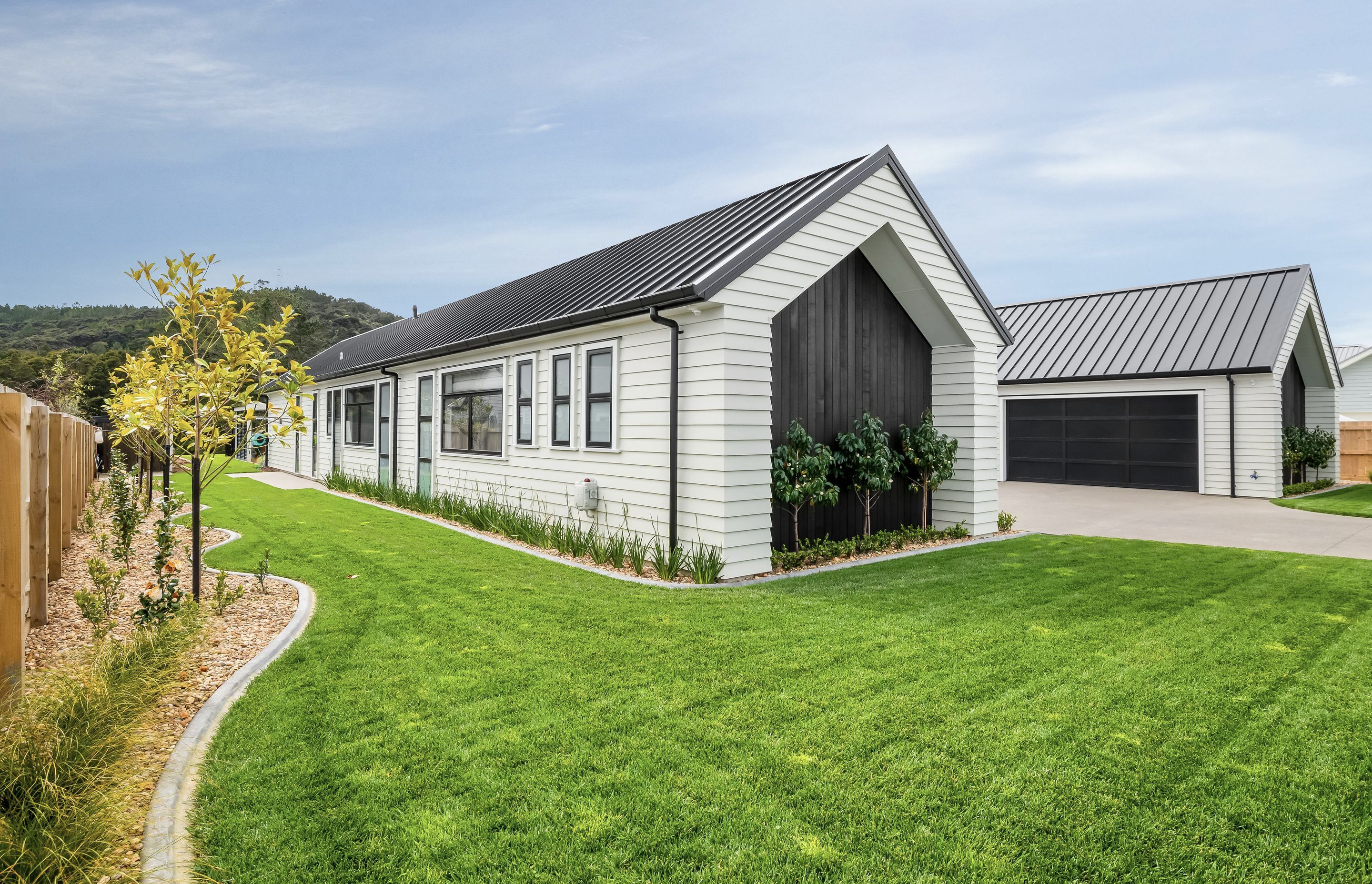 The H-shaped structure offers optimal privacy, with the windows of both wings and the paneled garage doors, crafted by Jones Doors, all perpendicular to the street.