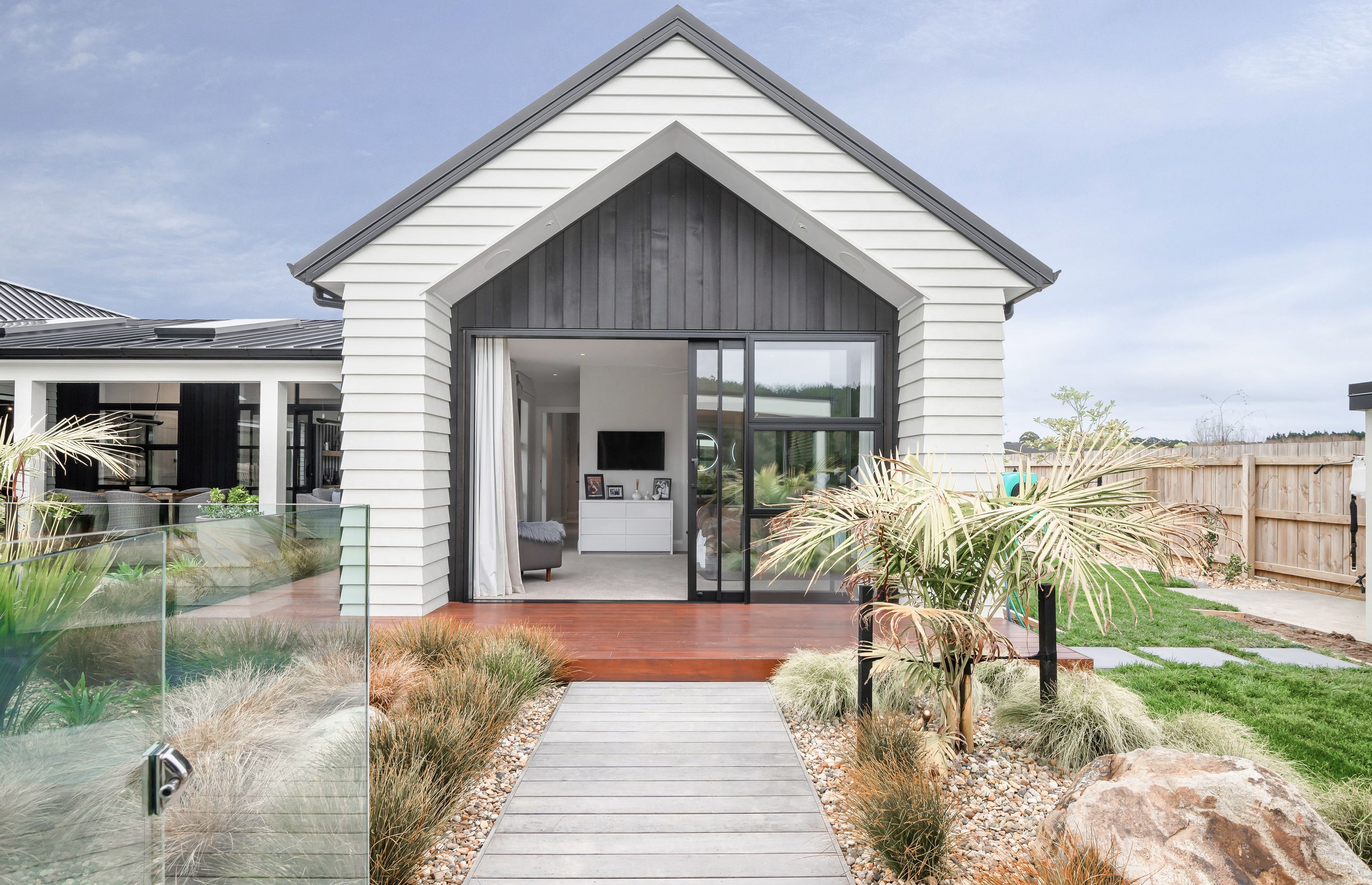Accents of black vertical cedar within jutting weatherboard frames make a feature of the end walls, marrying beautifully with the bold lines of the Spanlok 380 pan ribbed roof by Roof Industries.