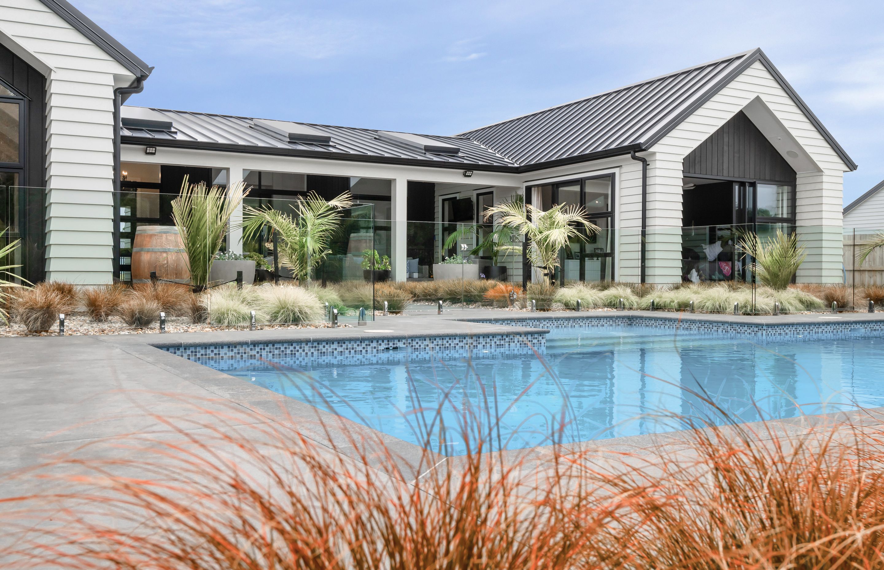 Resort-style landscaping by Green Living Landscaping connects this space to the generous pool, constructed by New Wave Pools.