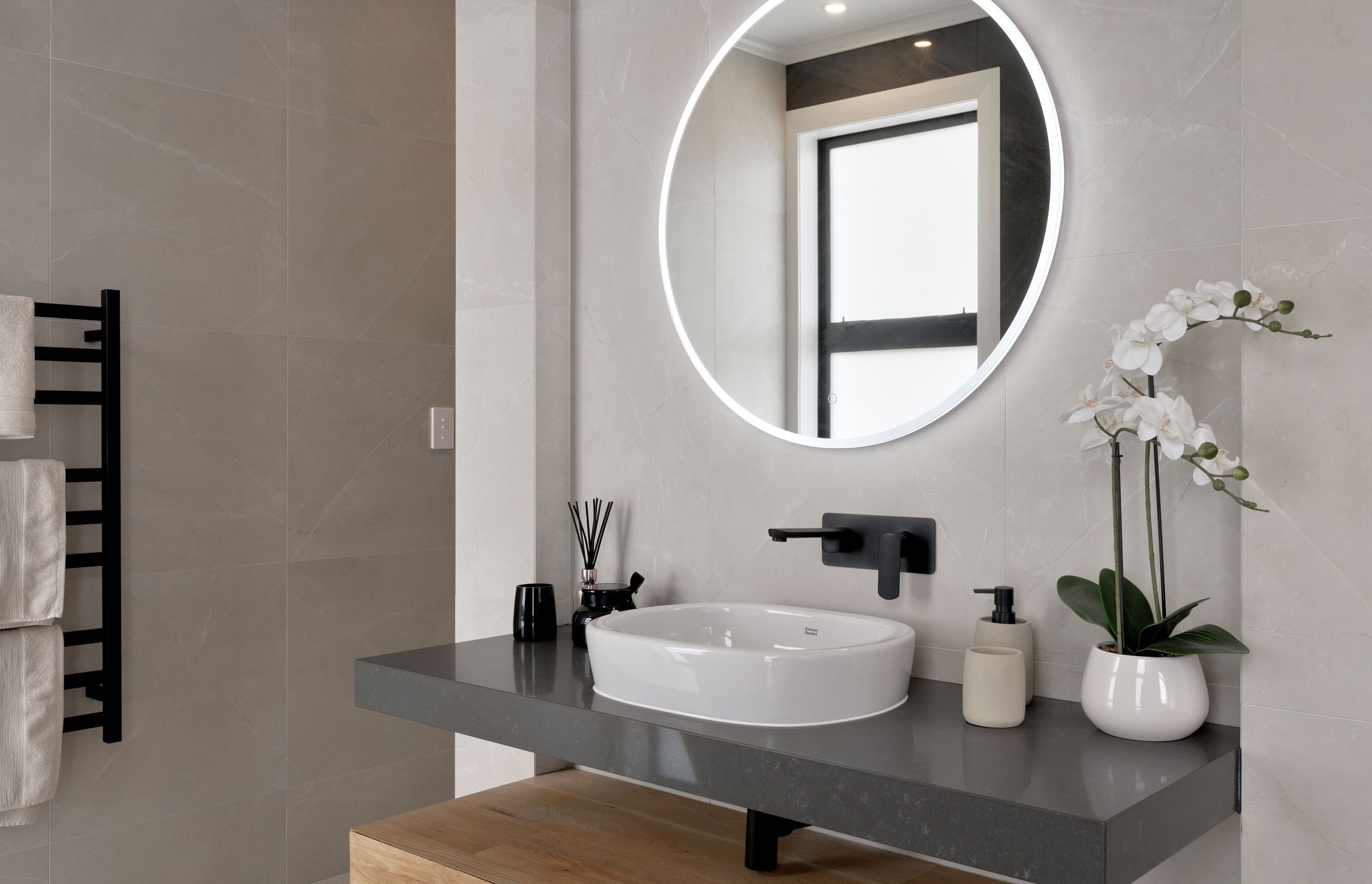 Each bathroom has a mix of stone, tiles, timber and black accents.