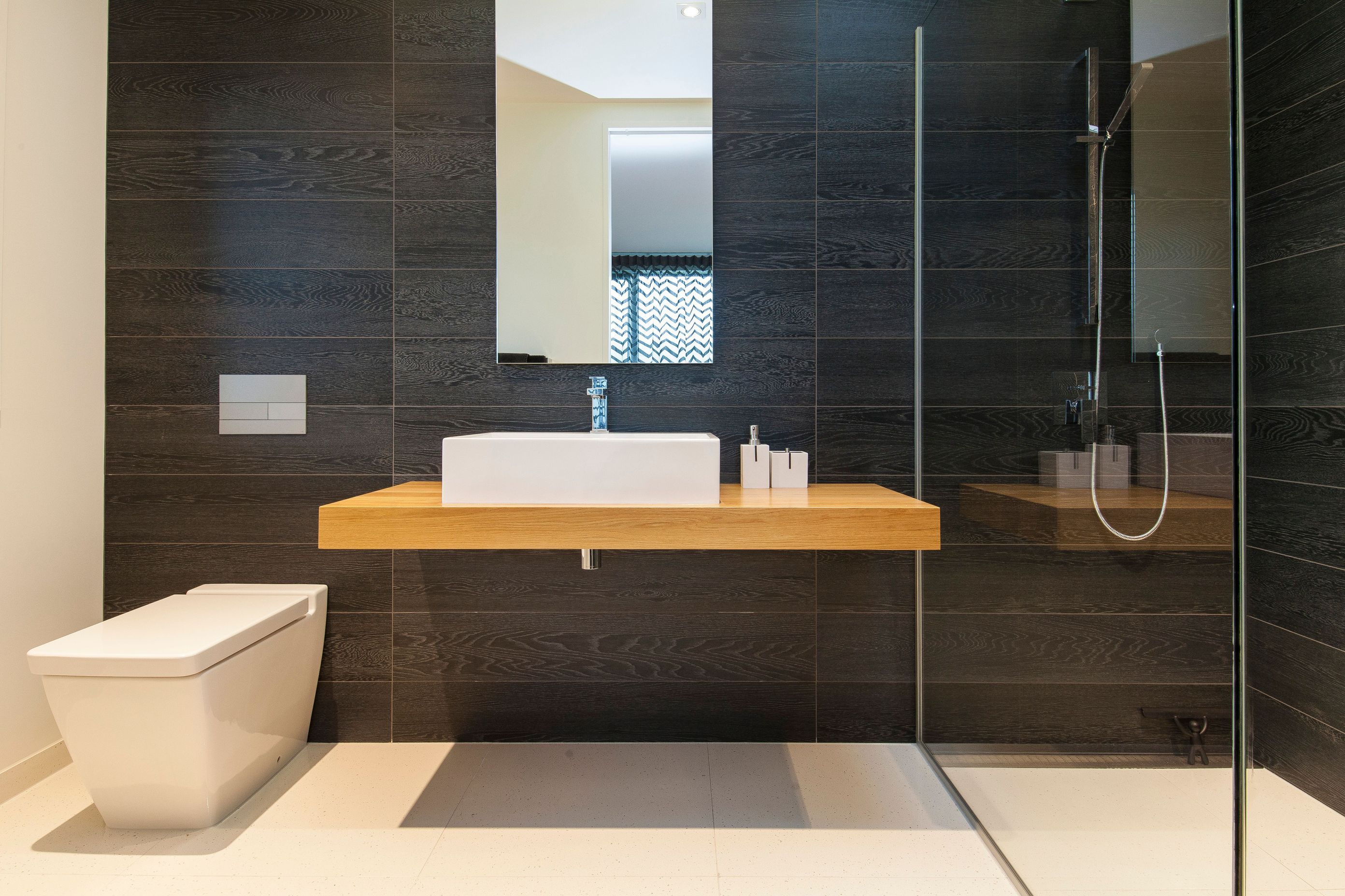 Timber-look tiles have been used on the walls of the bathrooms to echo the darkly stained exterior concrete finish.