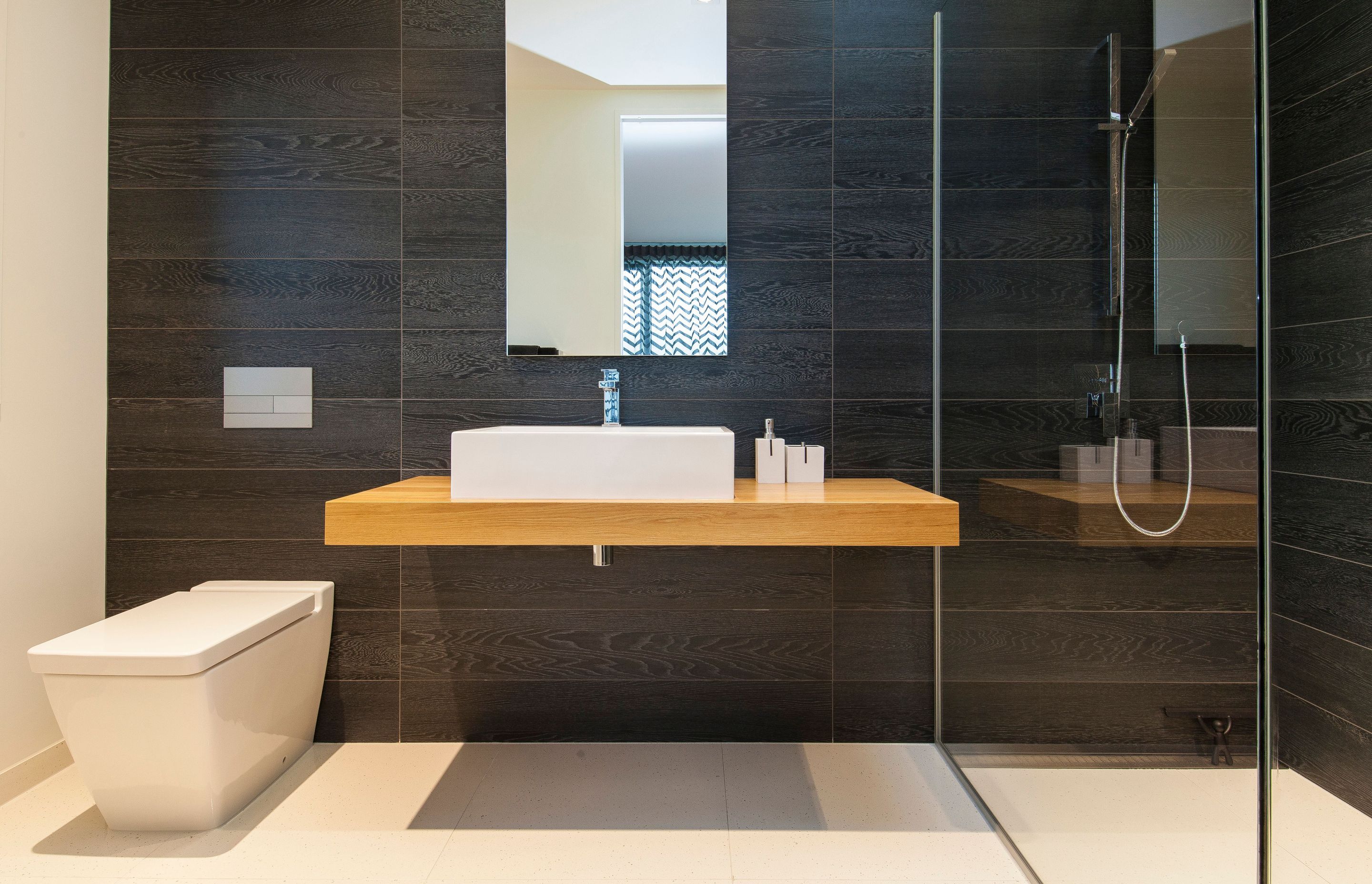 Timber-look tiles have been used on the walls of the bathrooms to echo the darkly stained exterior concrete finish.