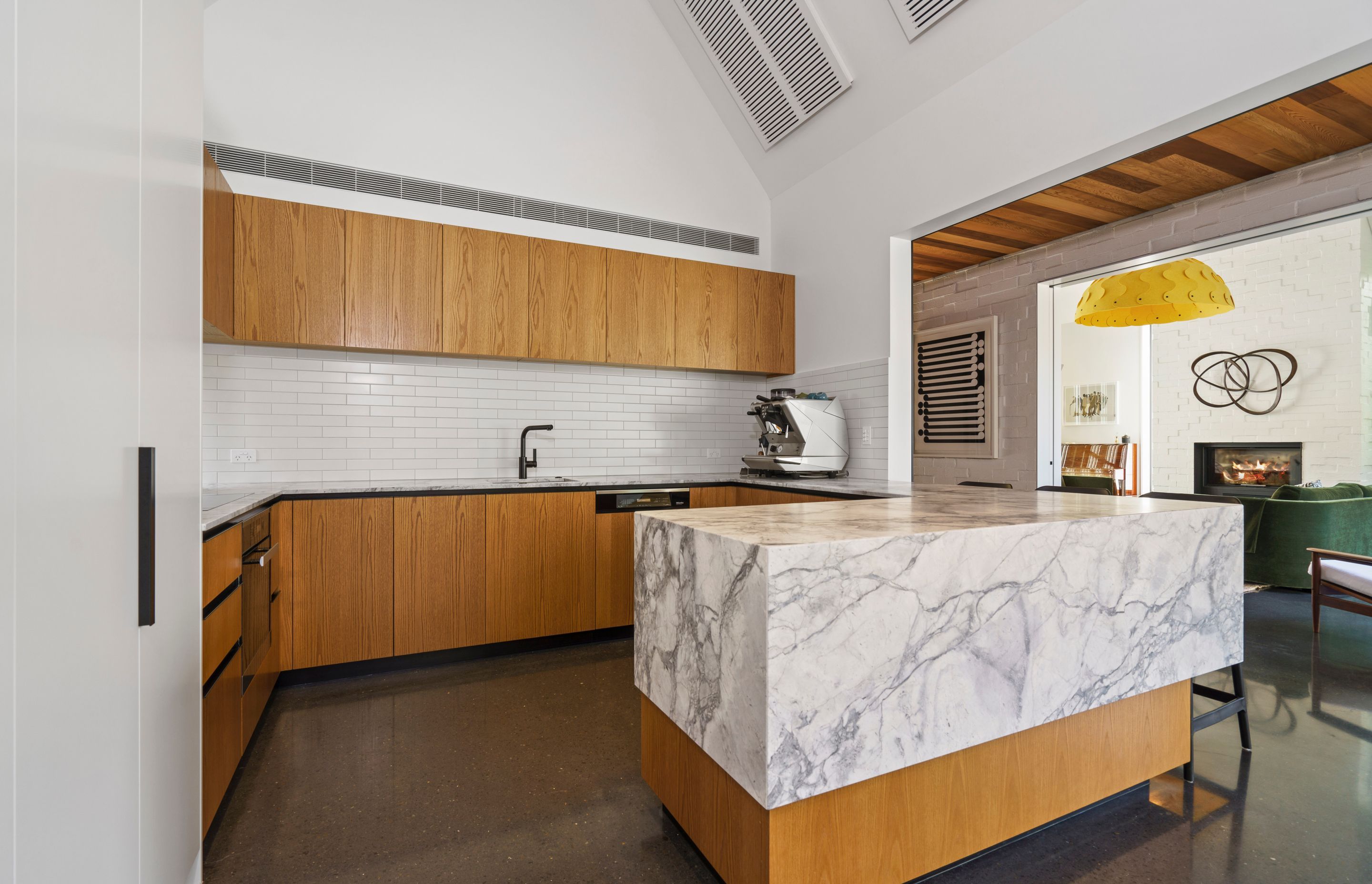 A dramatic peninsula-style island is a bold addition to the kitchen with the cool stone and warm timber complementing each other.