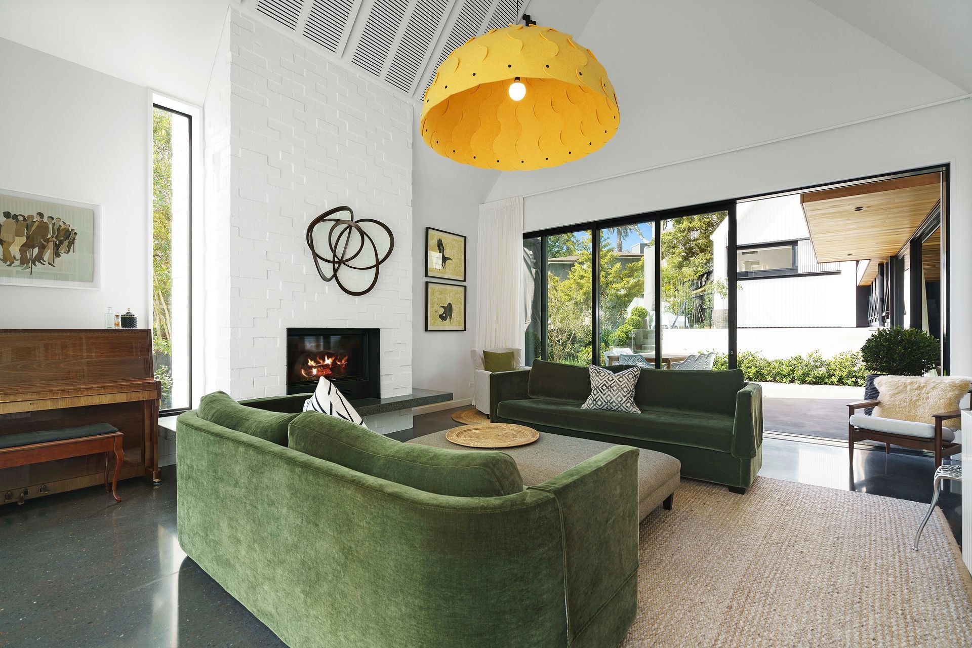 The skillion ceiling adds volumetric space to the living area while the bagged-brick chimney breast matches the exterior cladding of the white pavilions.
