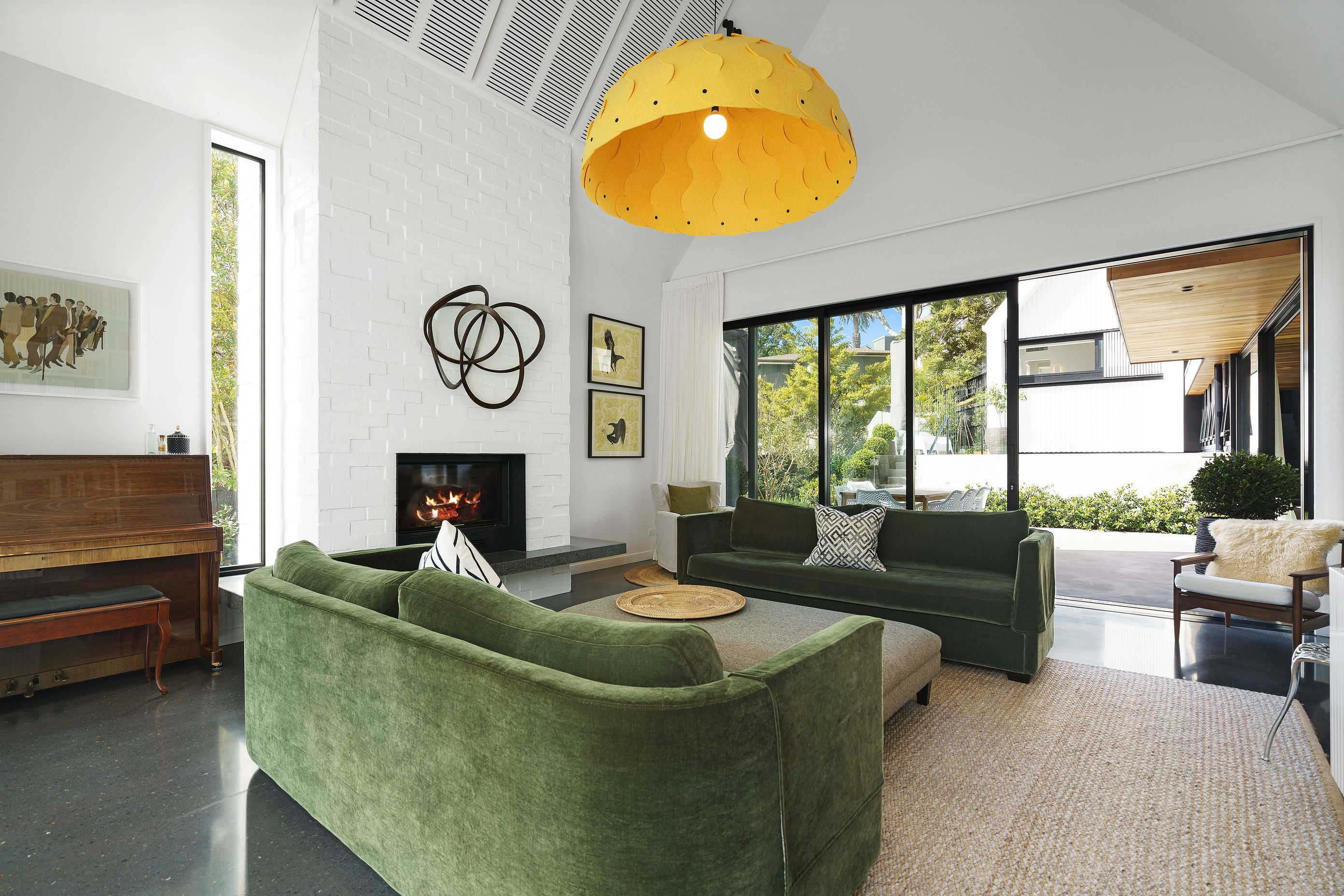 The skillion ceiling adds volumetric space to the living area while the bagged-brick chimney breast matches the exterior cladding of the white pavilions.