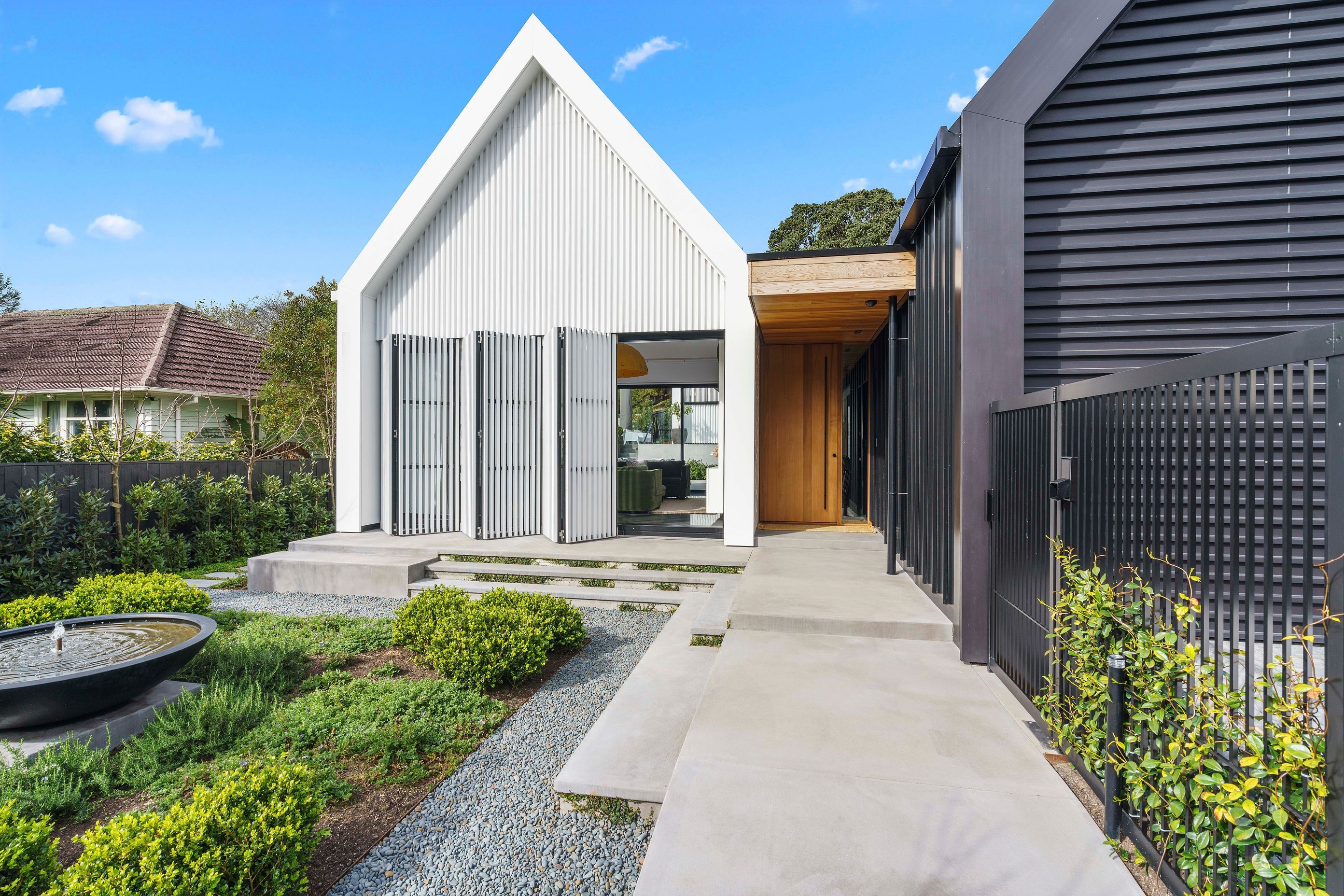 A bifolding slatted screen—which reads as a seamless wall when closed—provides privacy from the street while also mitigating solar gain.