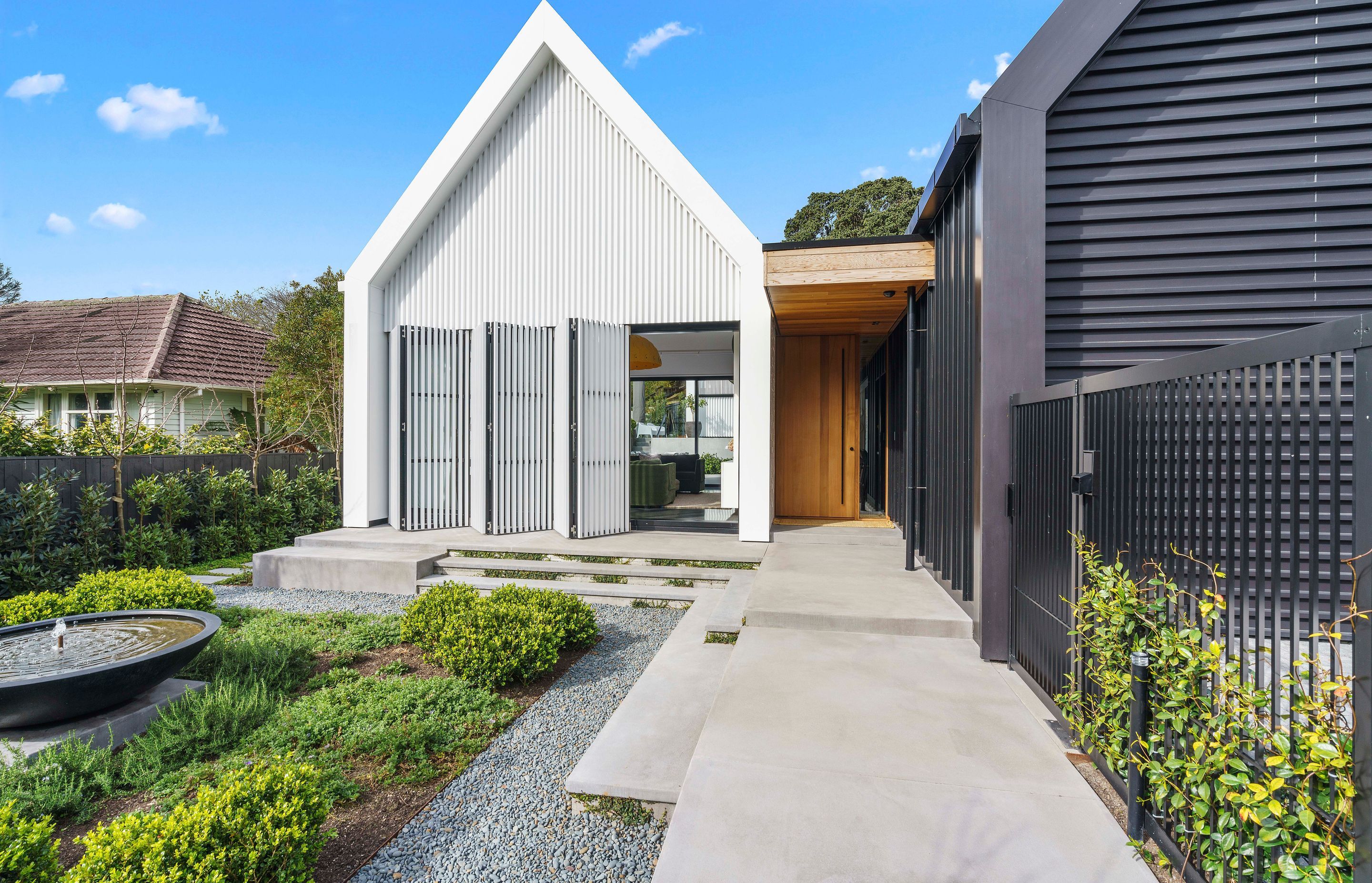 A bifolding slatted screen—which reads as a seamless wall when closed—provides privacy from the street while also mitigating solar gain.