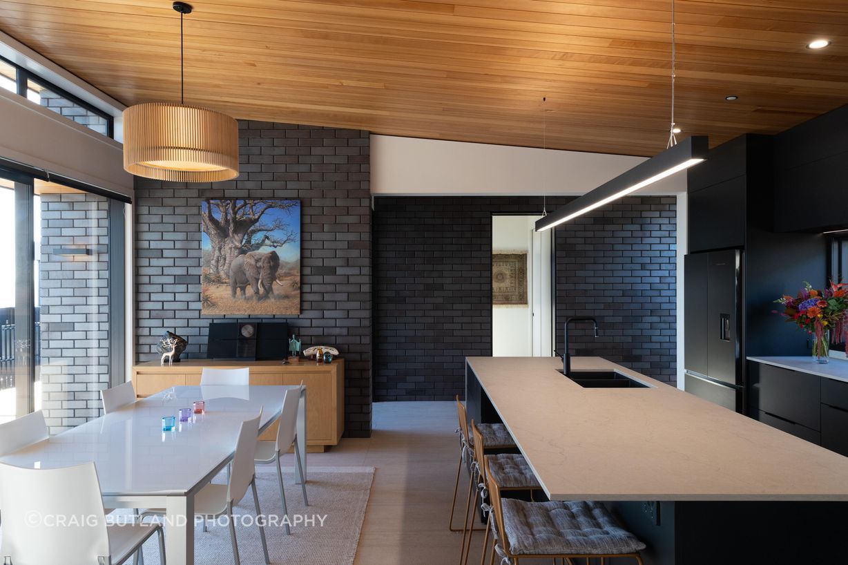 Brick veneer flows from outside into the main living space for seamless continuity, the timber ceiling adds warmth and a softer contrast to the deep brick finish.