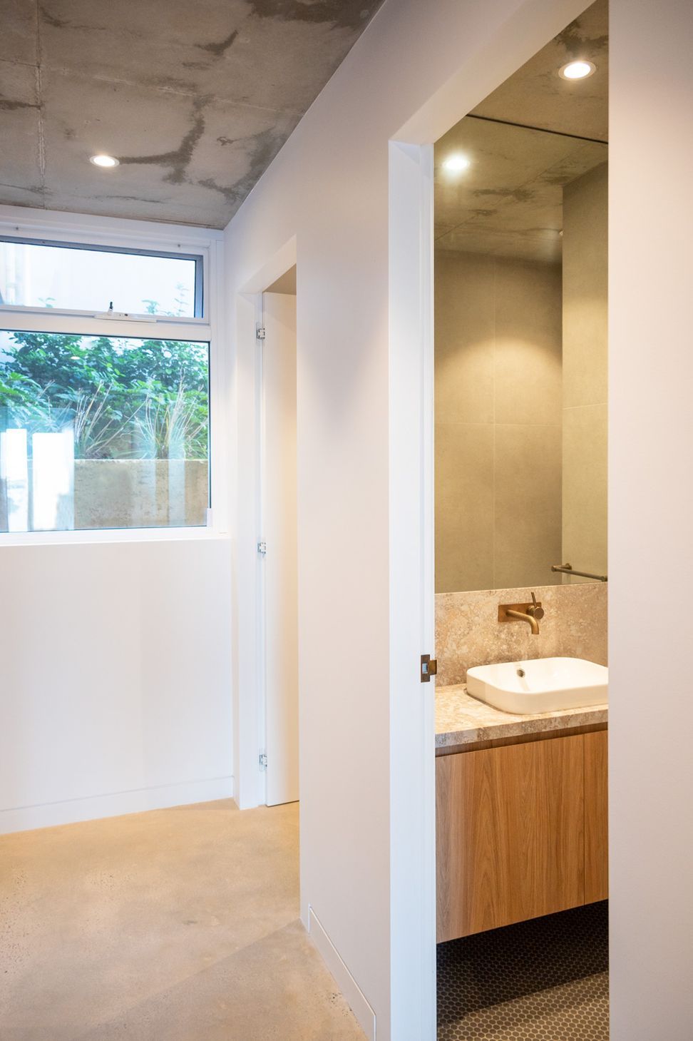 The hallway leading through to the bathroom holds minimal architectural detailing for a modern look.