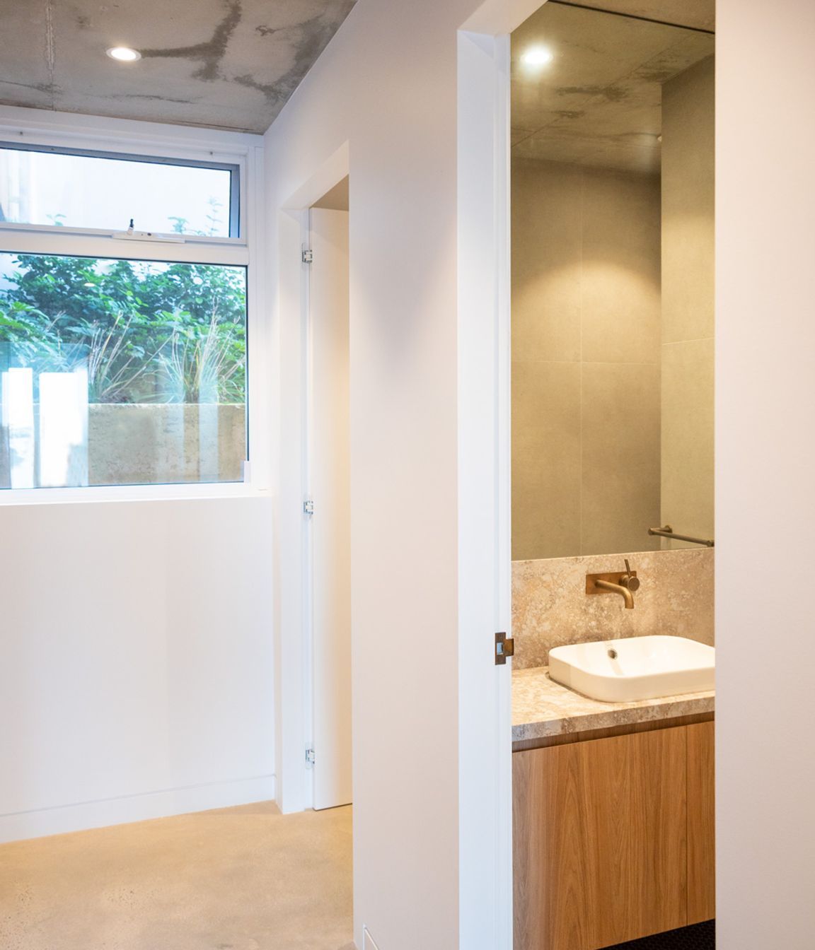 The hallway leading through to the bathroom holds minimal architectural detailing for a modern look.
