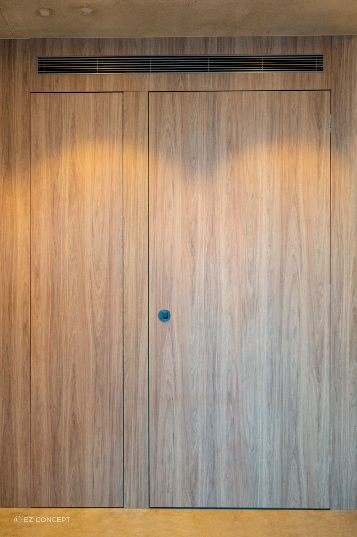 The timber façade of the ensuite wall conceals the door along its face.