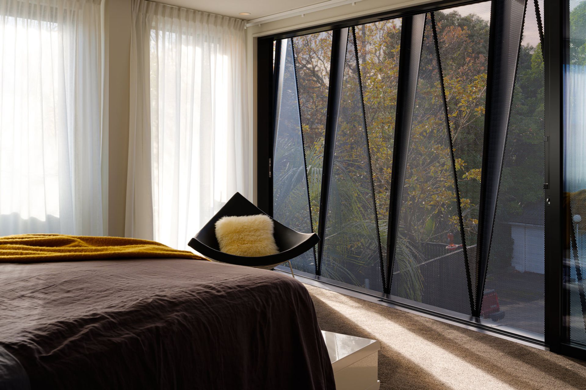 A wide-span sliding door in the main bedroom allows for natural ventilation. Sheer curtains on the north-facing facade allow for diffuse light throughout the day.