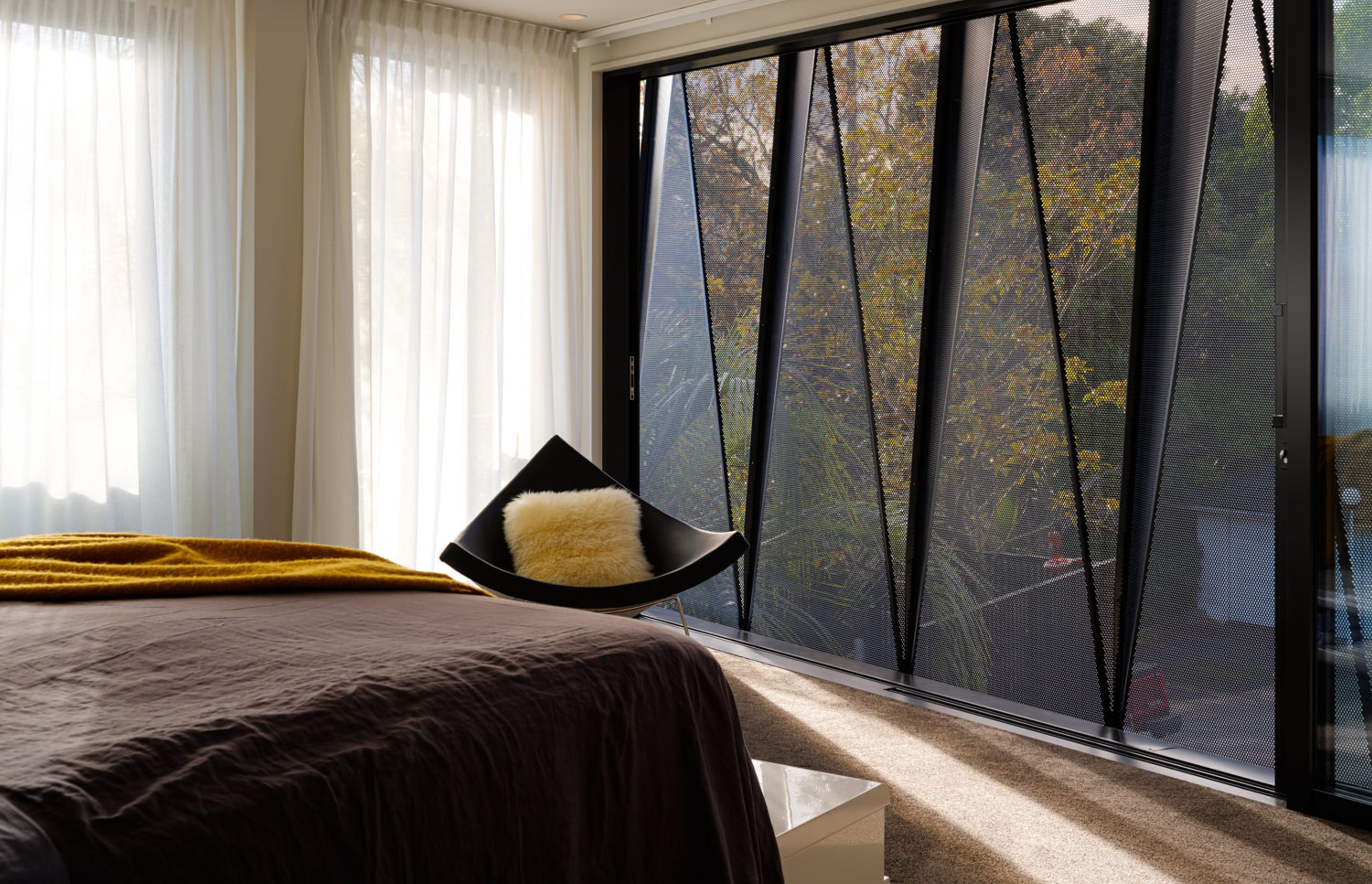 A wide-span sliding door in the main bedroom allows for natural ventilation. Sheer curtains on the north-facing facade allow for diffuse light throughout the day.