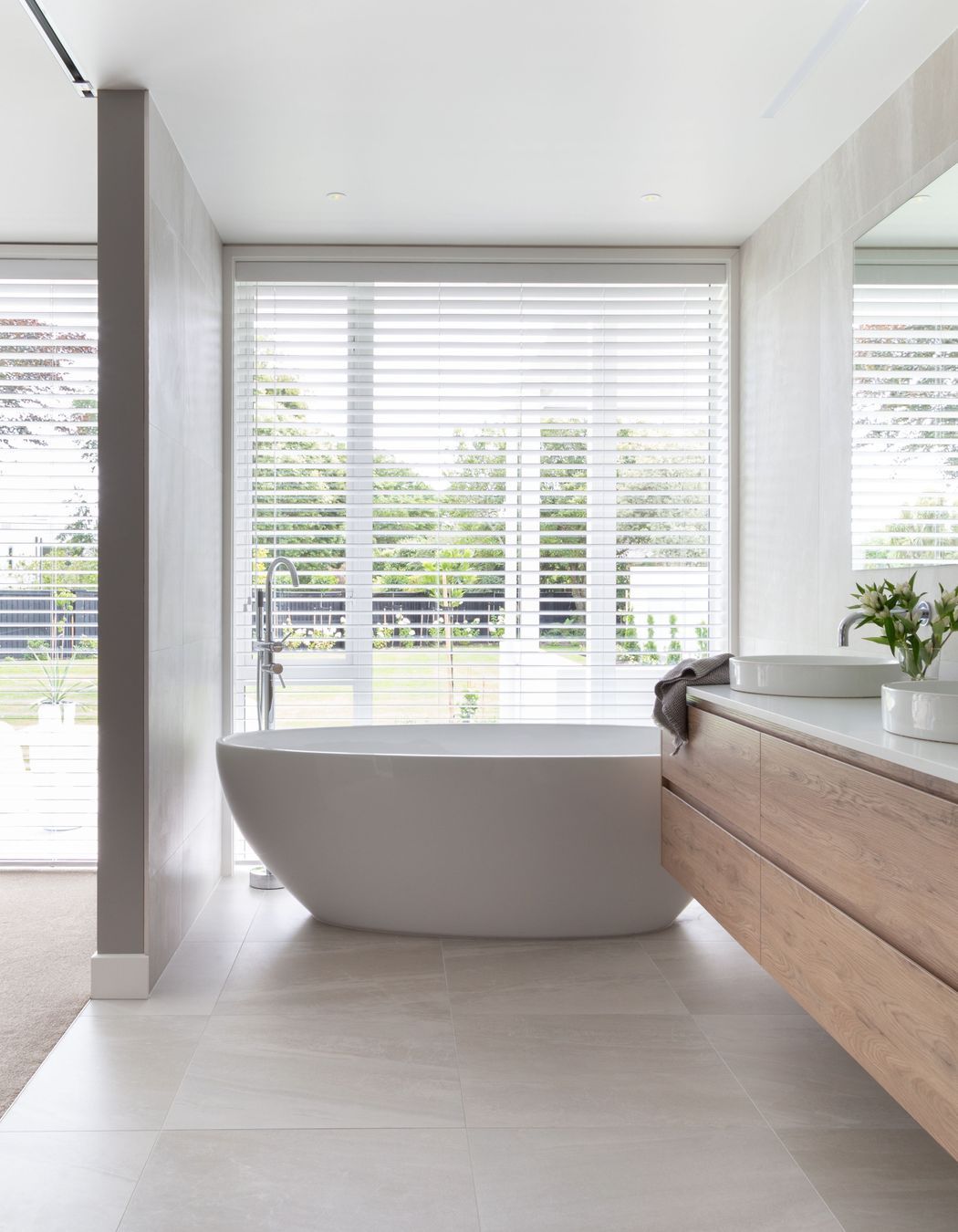 The master en suite's bath has an unobstructed view out to the backyard, while operable shutters provide privacy.