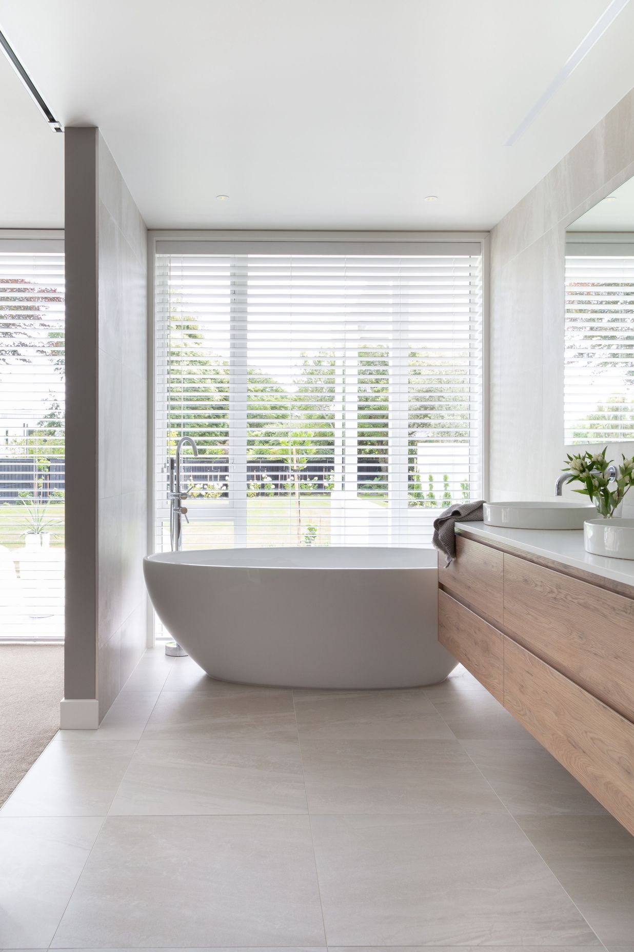 The master en suite's bath has an unobstructed view out to the backyard, while operable shutters provide privacy.