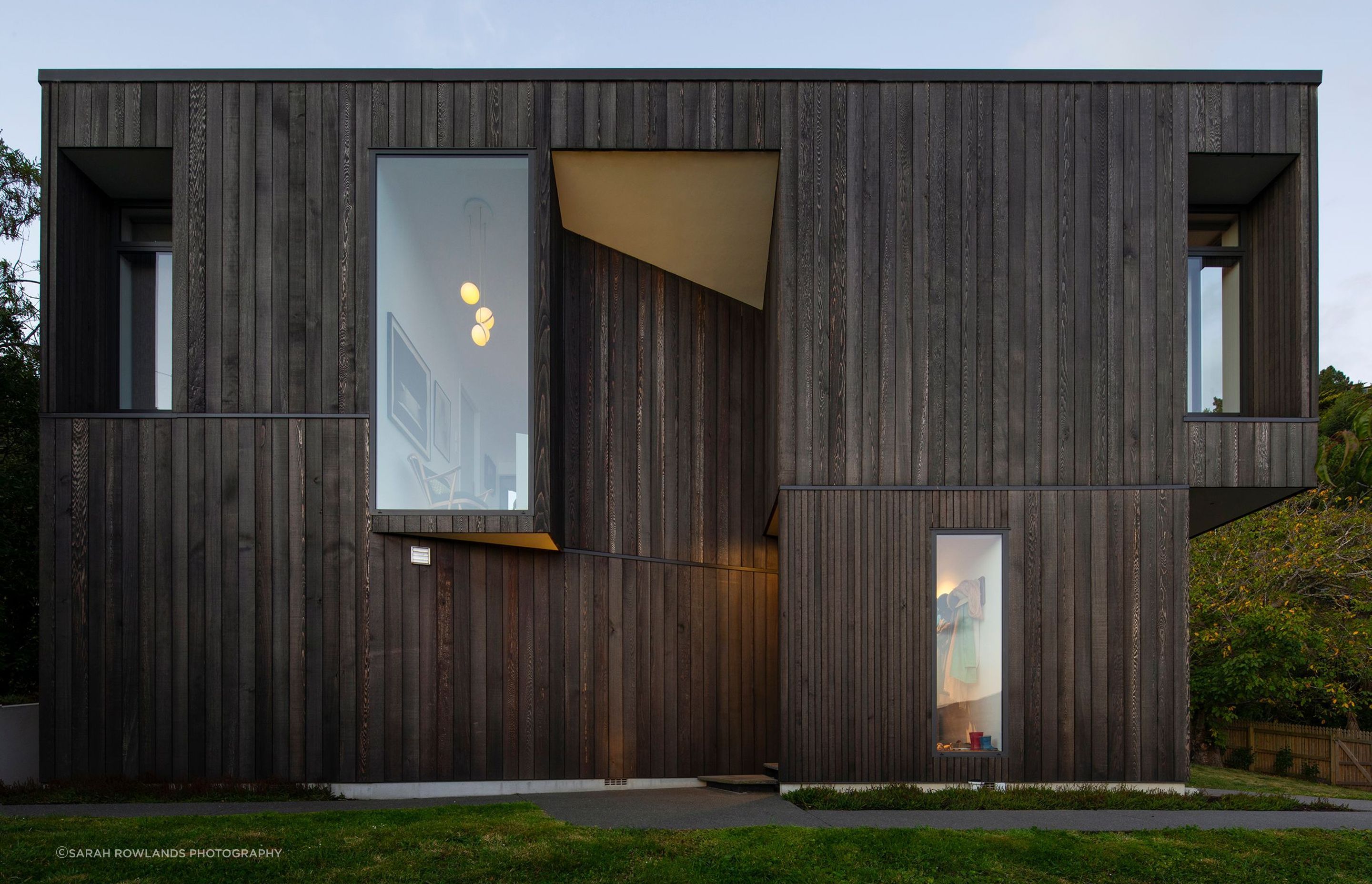 The home's folded geometry celebrates strong shapes with interesting cut-outs that reflect the nearby rocky outcrop of the Port Hills.