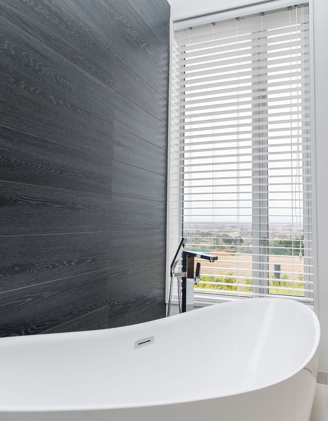 A picture window provides a far-reaching vista to enjoy from the free-standing tub.
