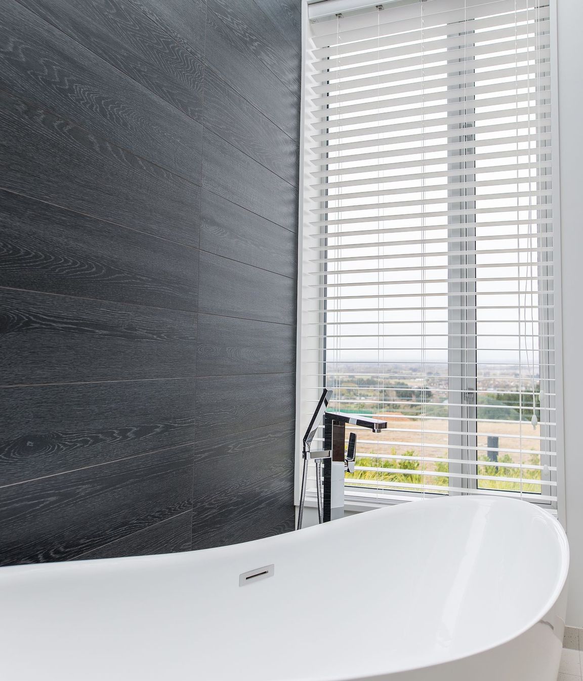 A picture window provides a far-reaching vista to enjoy from the free-standing tub.