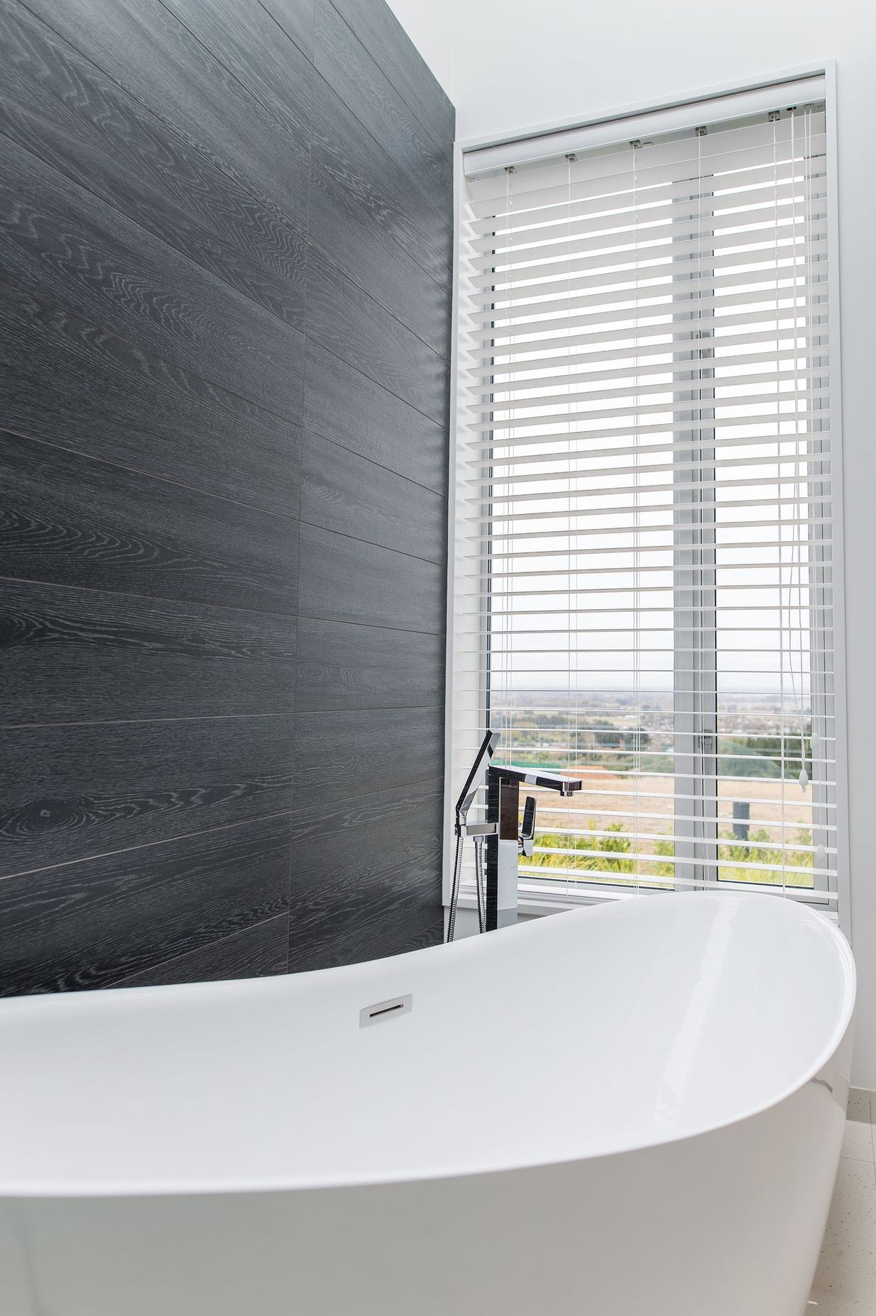 A picture window provides a far-reaching vista to enjoy from the free-standing tub.