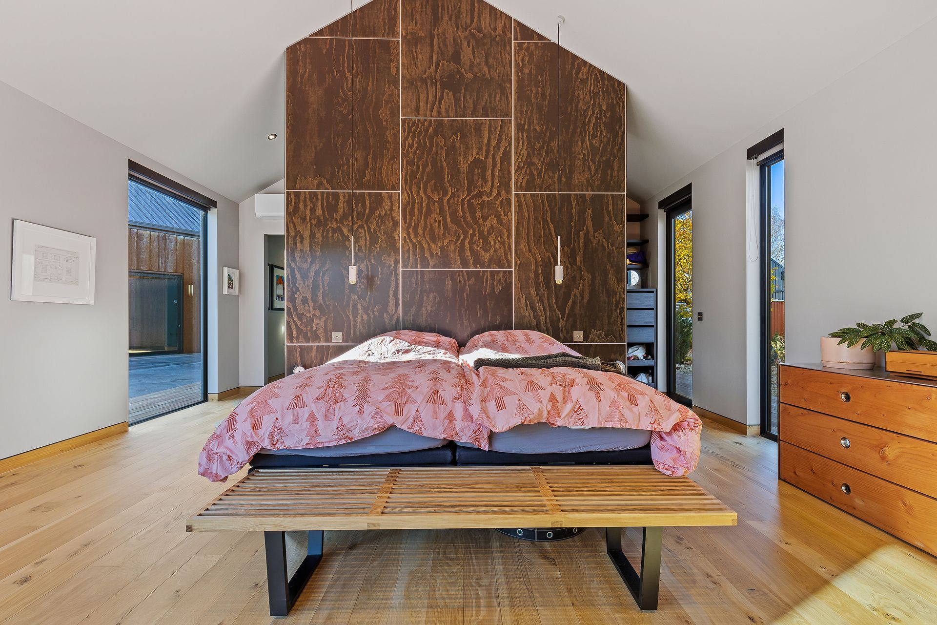 A custom floor-to-ceiling panelled wall acts as a headboard and allows for privacy in the walk-in-wardrobe.