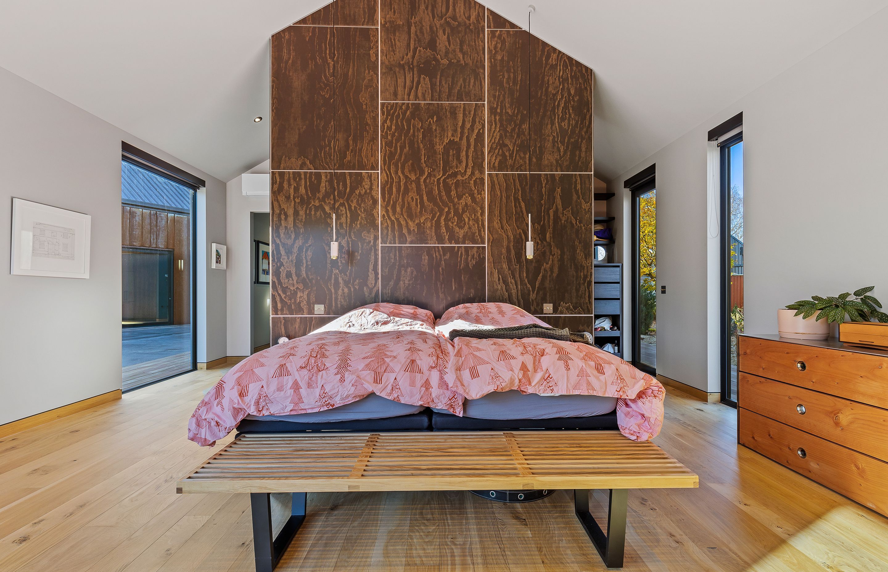 A custom floor-to-ceiling panelled wall acts as a headboard and allows for privacy in the walk-in-wardrobe.