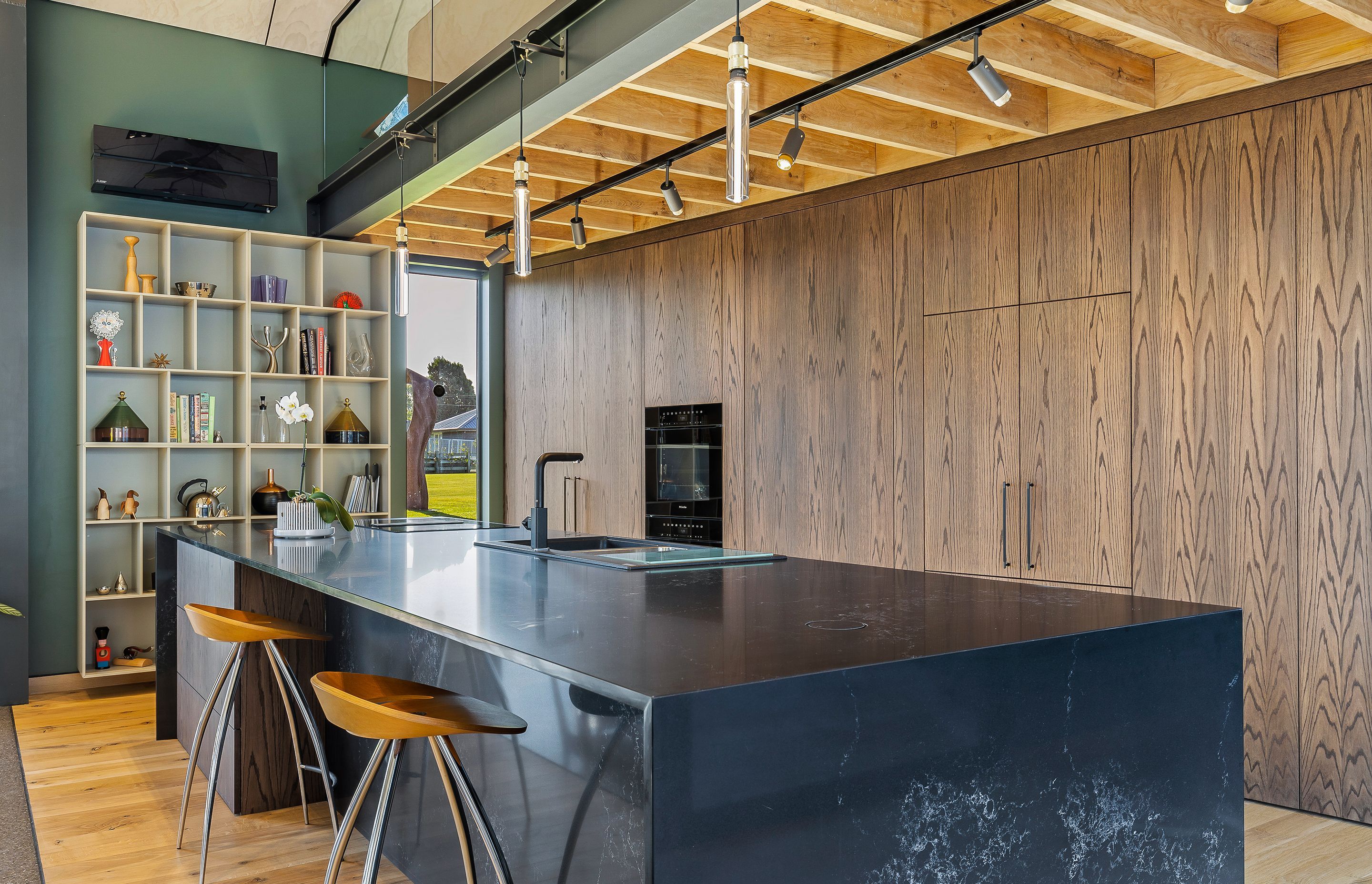 The dark granite kitchen island bench has an integrated sink and cooktop.