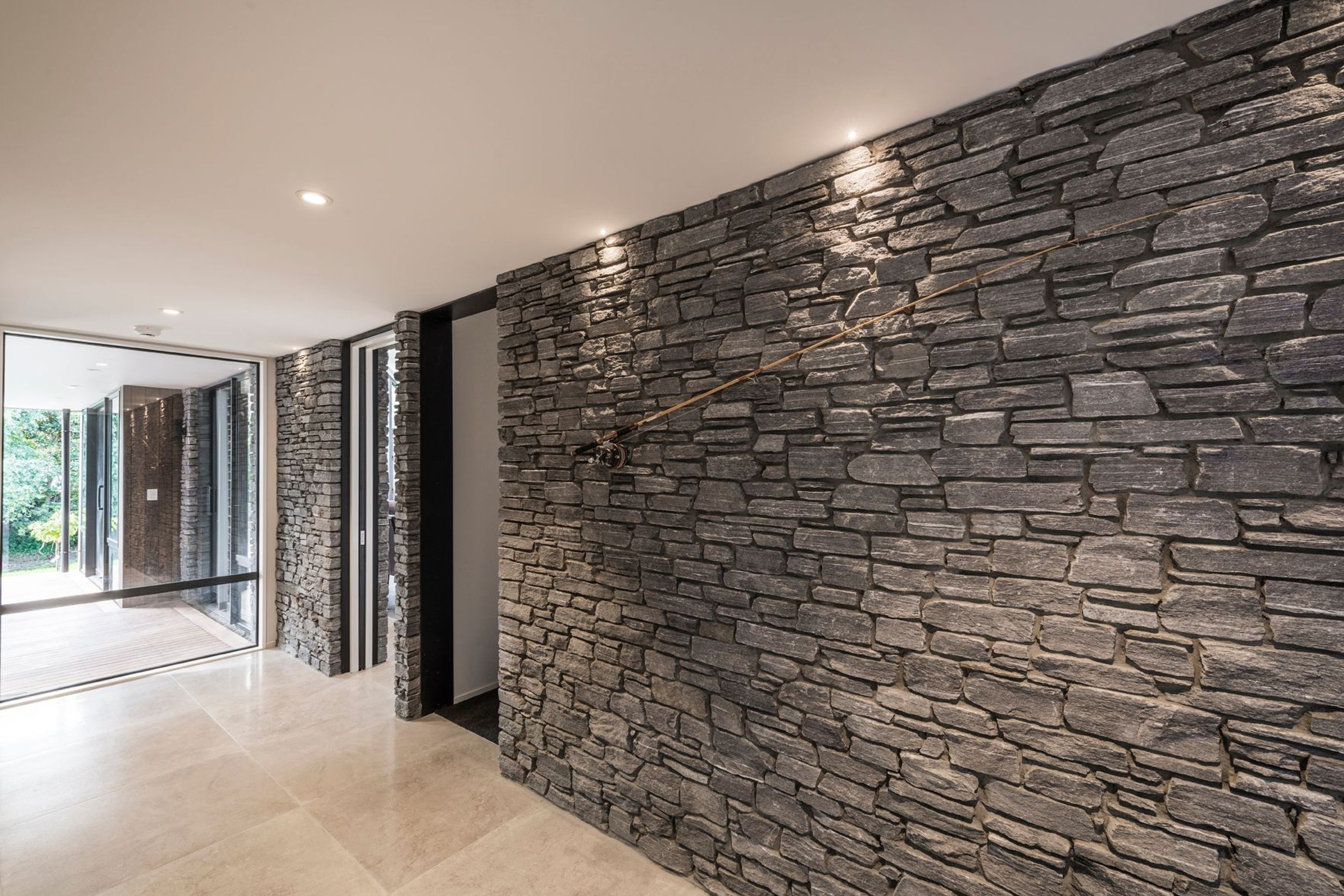 A wall of stone on one side of the entry hall, runs right through the home into the kitchen/dining space.