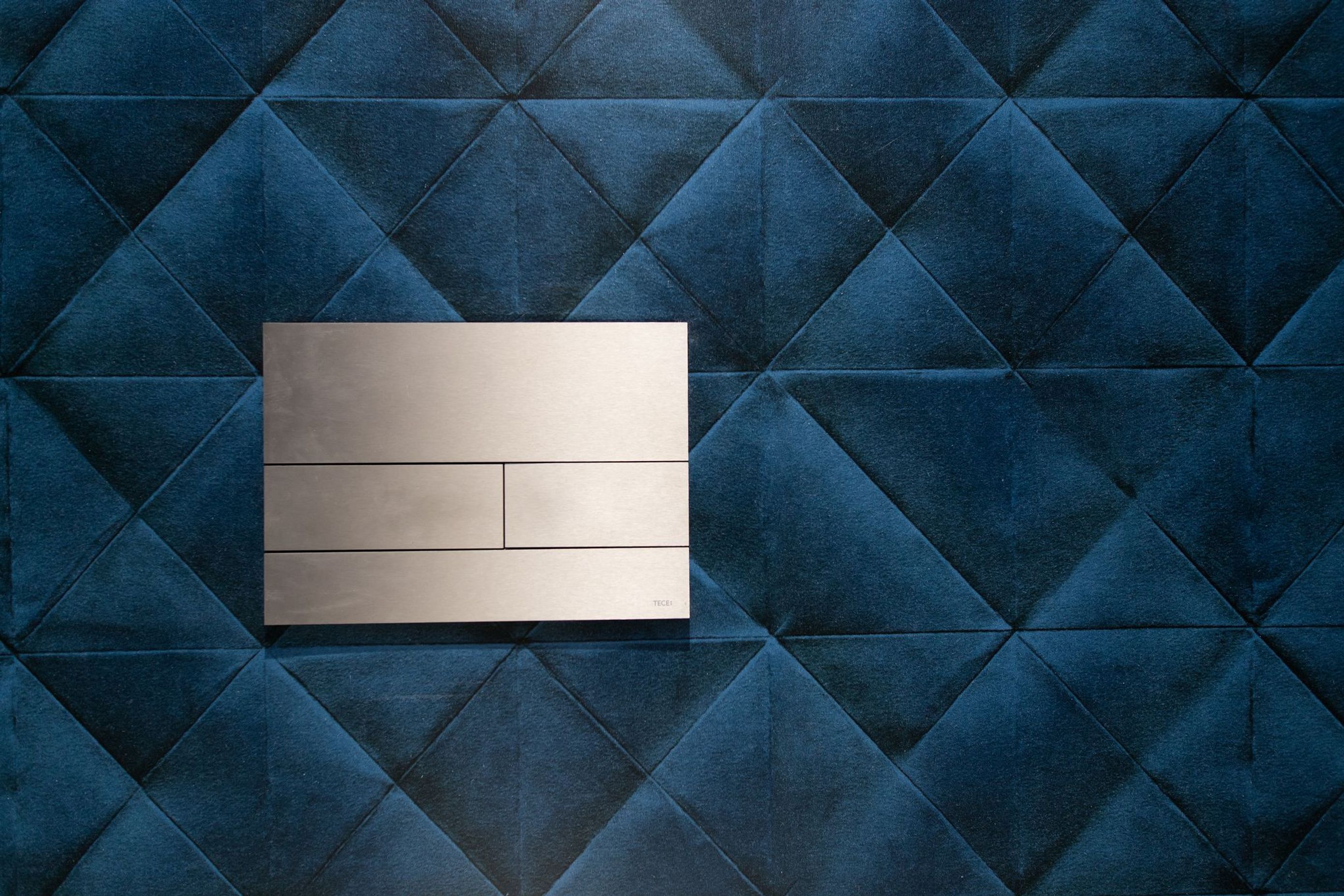 The statement wallpaper adds a further layer of plush elegance with its quilted velvet appearance.