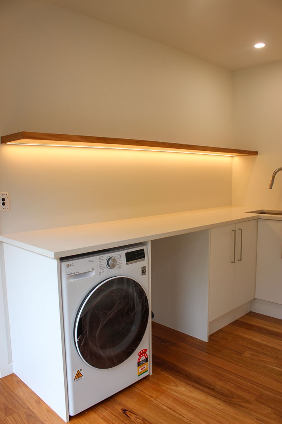 Blackbutt (Pilularis) timber overlay on the floors and the custom built floating shelf give this functional laundry a high-end & luxurious feel. Keeping on top of the all laundry for a growing and busy family needn't be a chore with a space like this