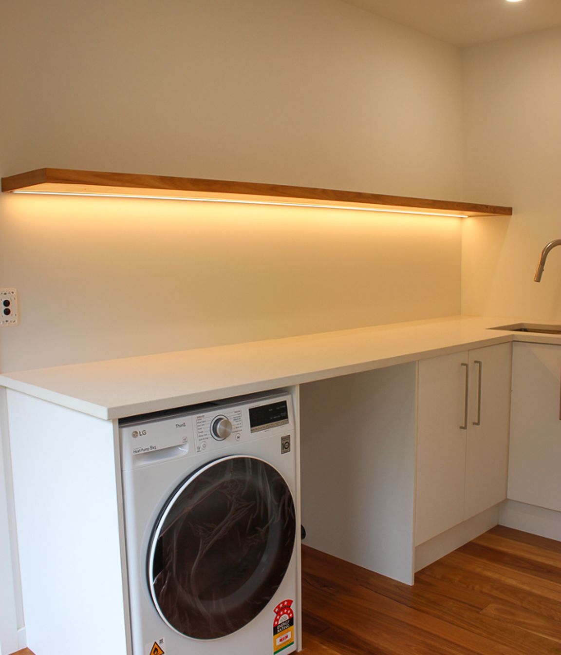 Blackbutt (Pilularis) timber overlay on the floors and the custom built floating shelf give this functional laundry a high-end &amp; luxurious feel.  Keeping on top of the all laundry for a growing and busy family needn't be a chore with a space like this