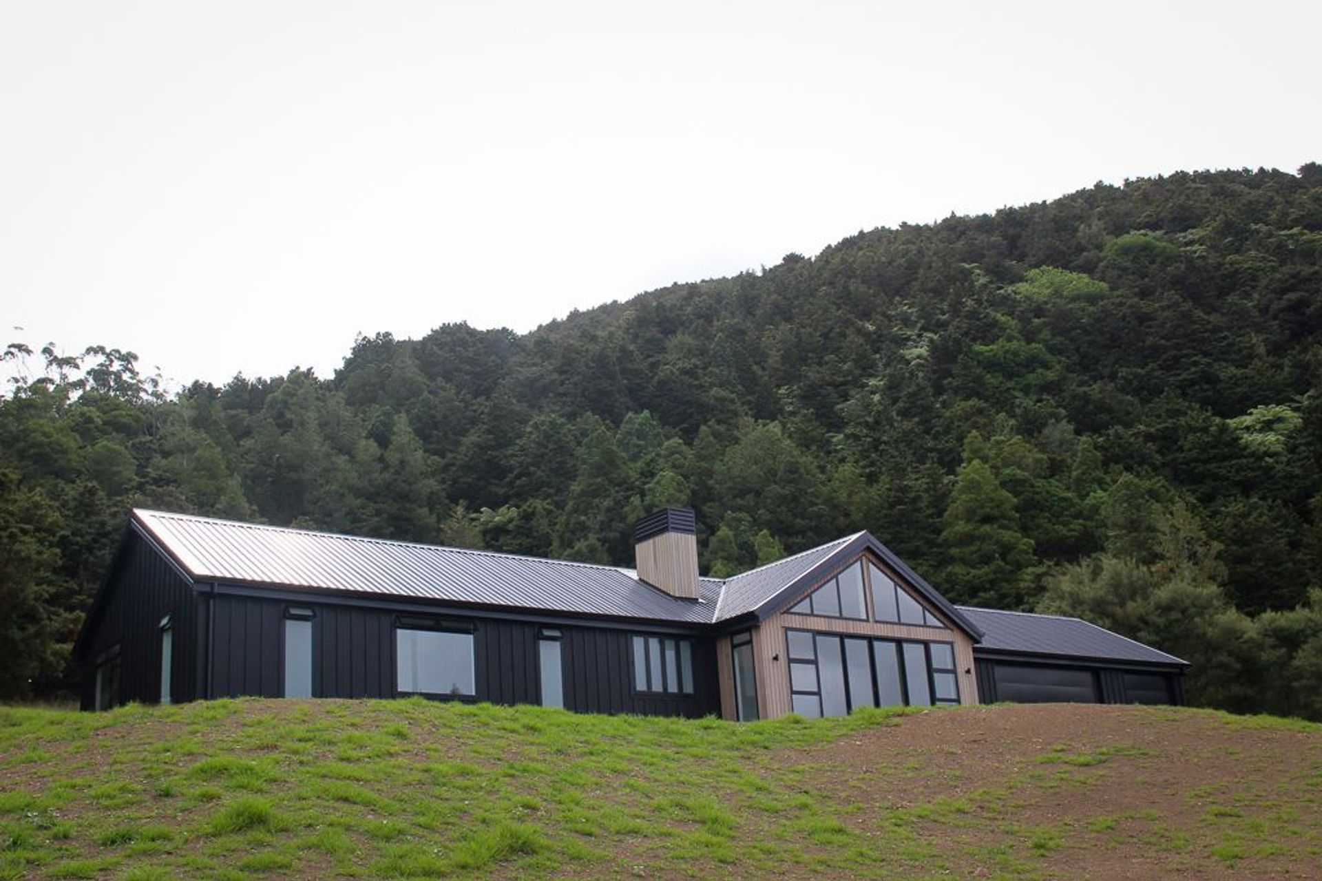 Clad in black Triclad board & Batten with Cedar gables & a custom built cedar clad chimney with powdercoated cowling. This family home sits proudly in its rural setting