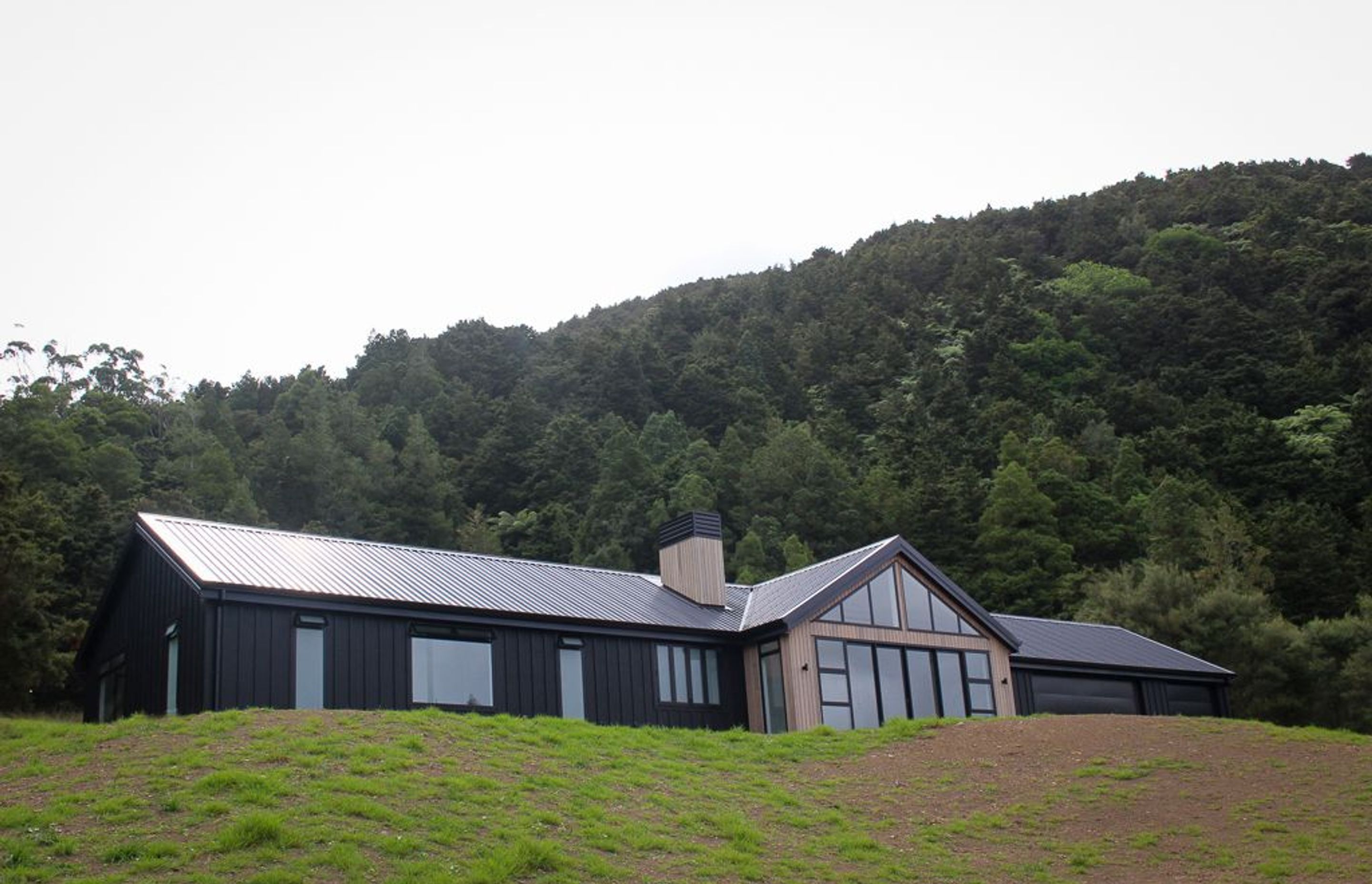 Clad in black Triclad board &amp; Batten with Cedar gables &amp; a custom built cedar clad chimney with powdercoated cowling.  This family home sits proudly in its rural setting