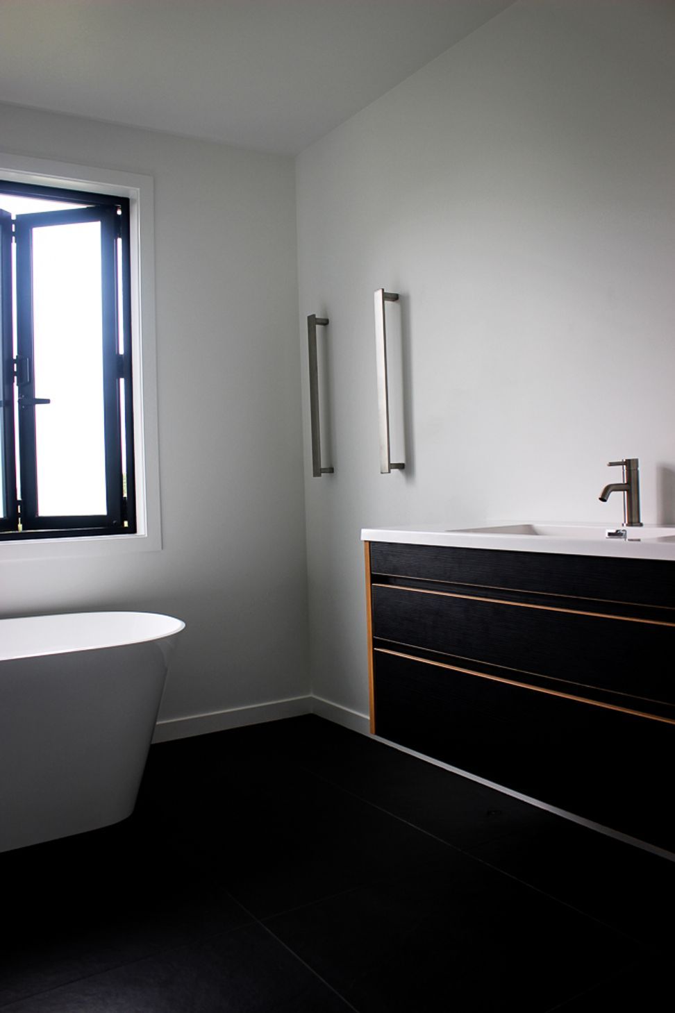 Tiled floors, Black & Ply Vanity and vertical towel rails keep this family bathroom looking contemporary and luxurious. Bathroom hardware supplied by Elite Bathrooms