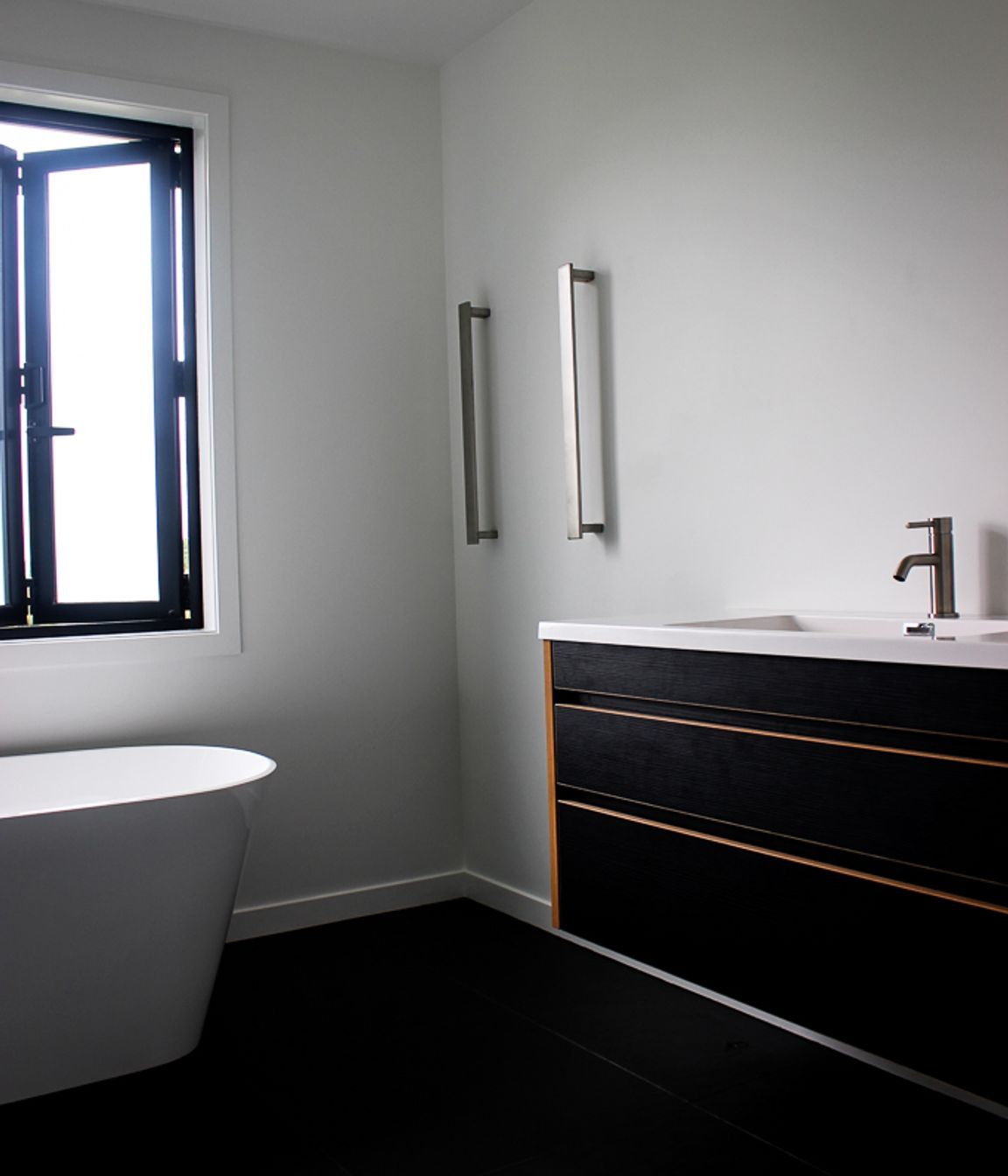 Tiled floors, Black &amp; Ply Vanity and vertical towel rails keep this family bathroom looking contemporary and luxurious.  Bathroom hardware supplied by Elite Bathrooms