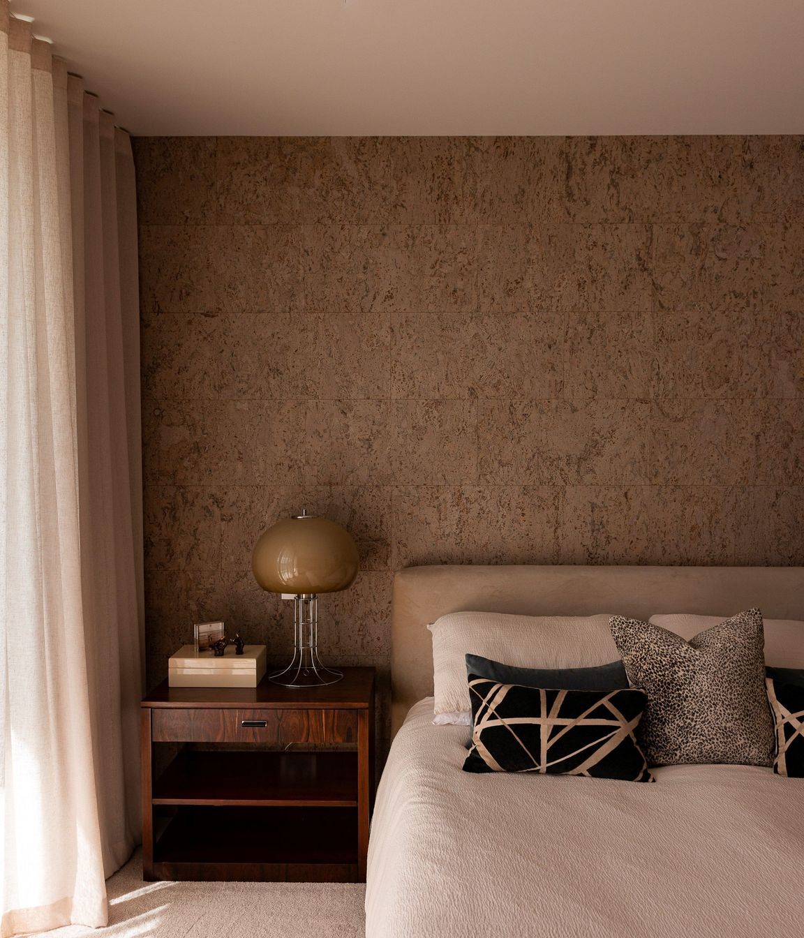 The cork feature wall brings warmth and texture to the bedroom.