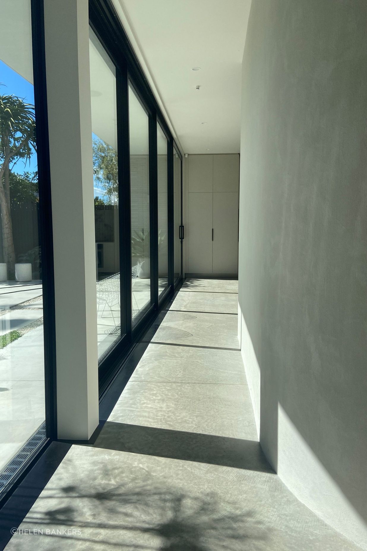 The gentle curve of the hallway wall guides you into the open-plan kitchen, dining, and living space.