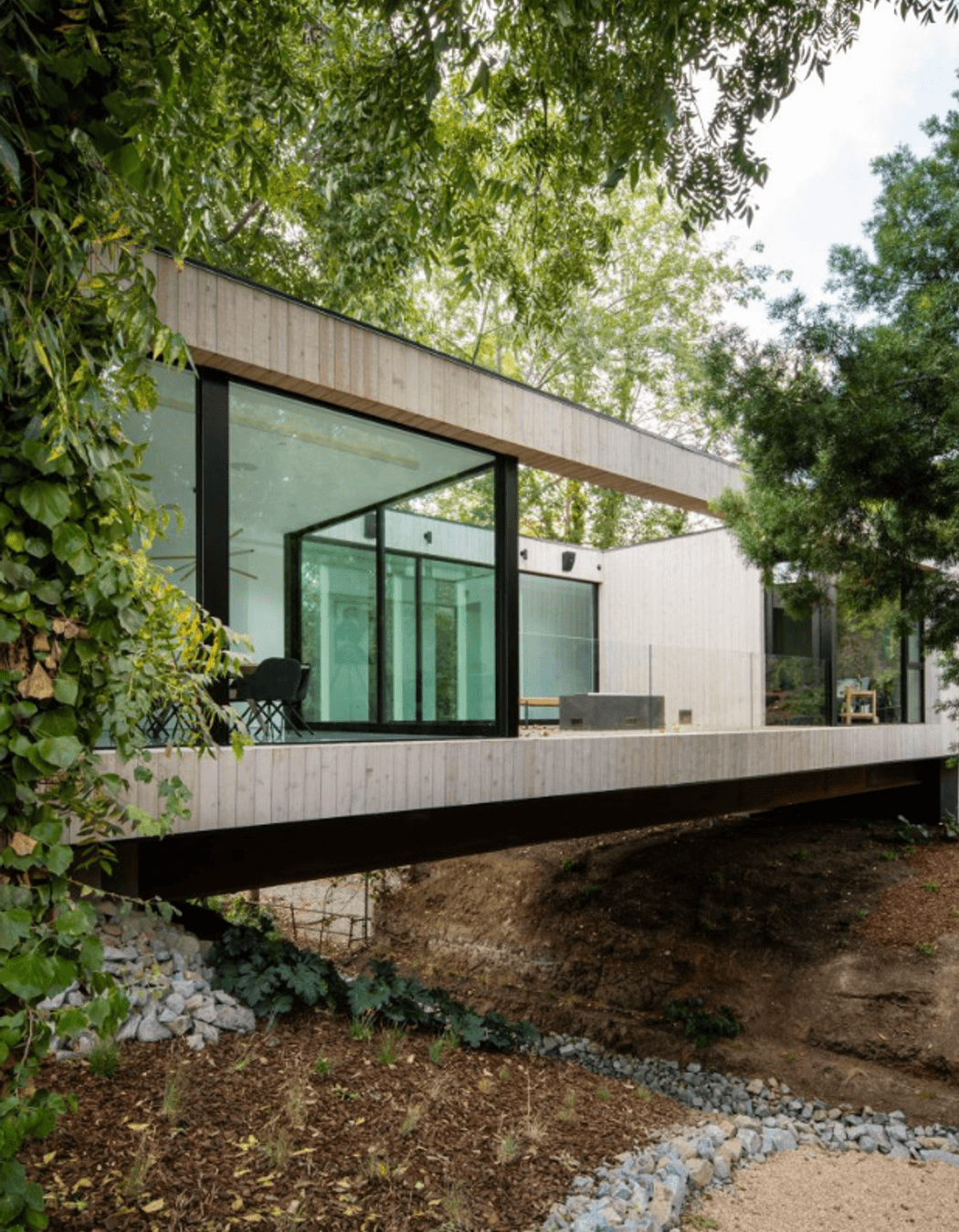 Living up to its name - a corridor of the house traverses a central bridge over a stream.