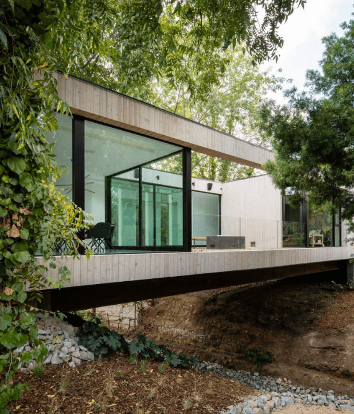 Living up to its name - a corridor of the house traverses a central bridge over a stream.