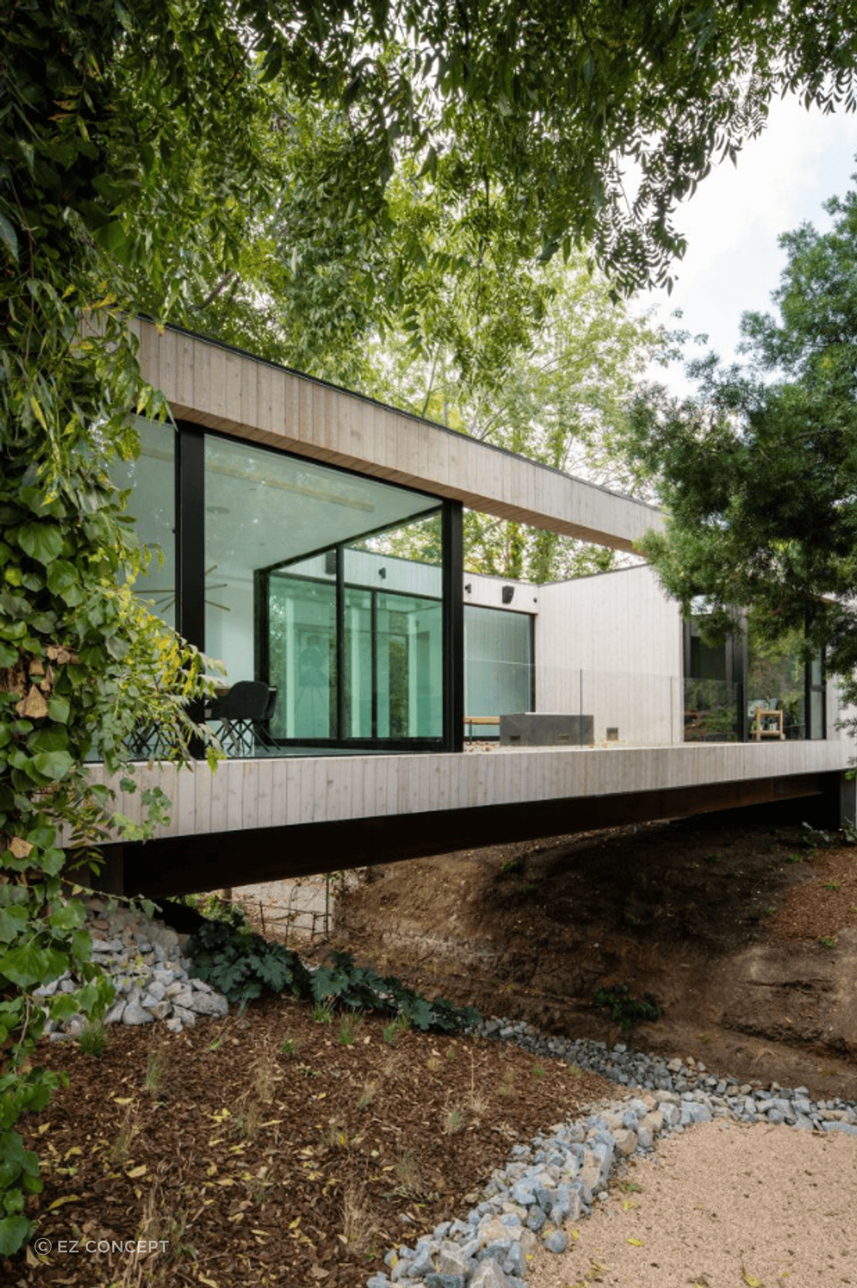Living up to its name - a corridor of the house traverses a central bridge over a stream.