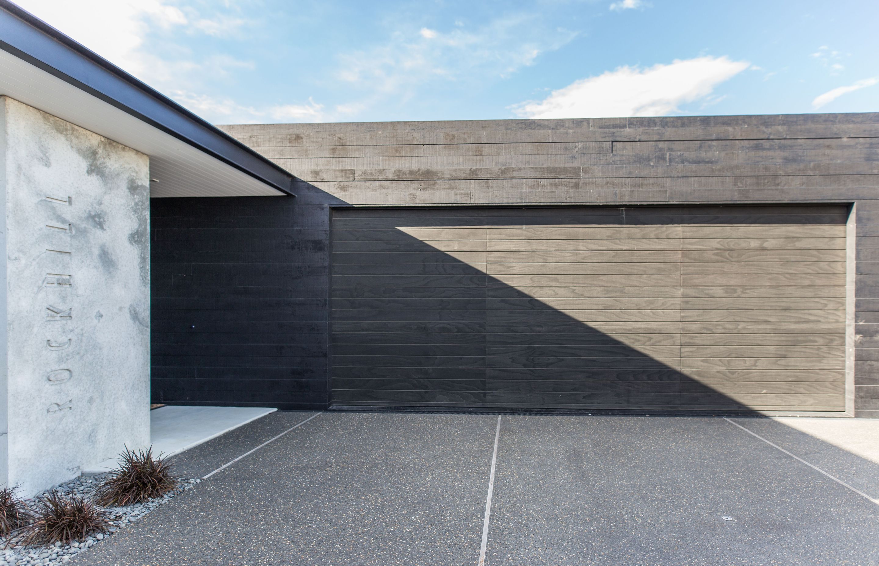 The plan features two separate forms, one private (containing the garage and guest bedrooms) painted black and one public, which has been left as raw concrete.