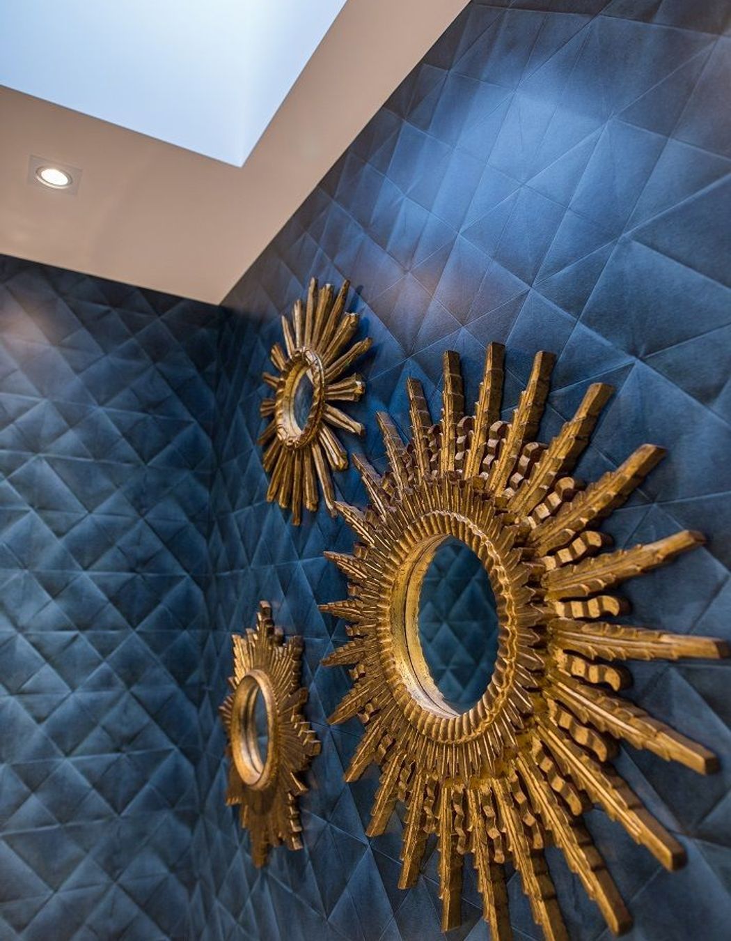 A trio of ornate gilt mirrors bring a sense of drama to the powder room.