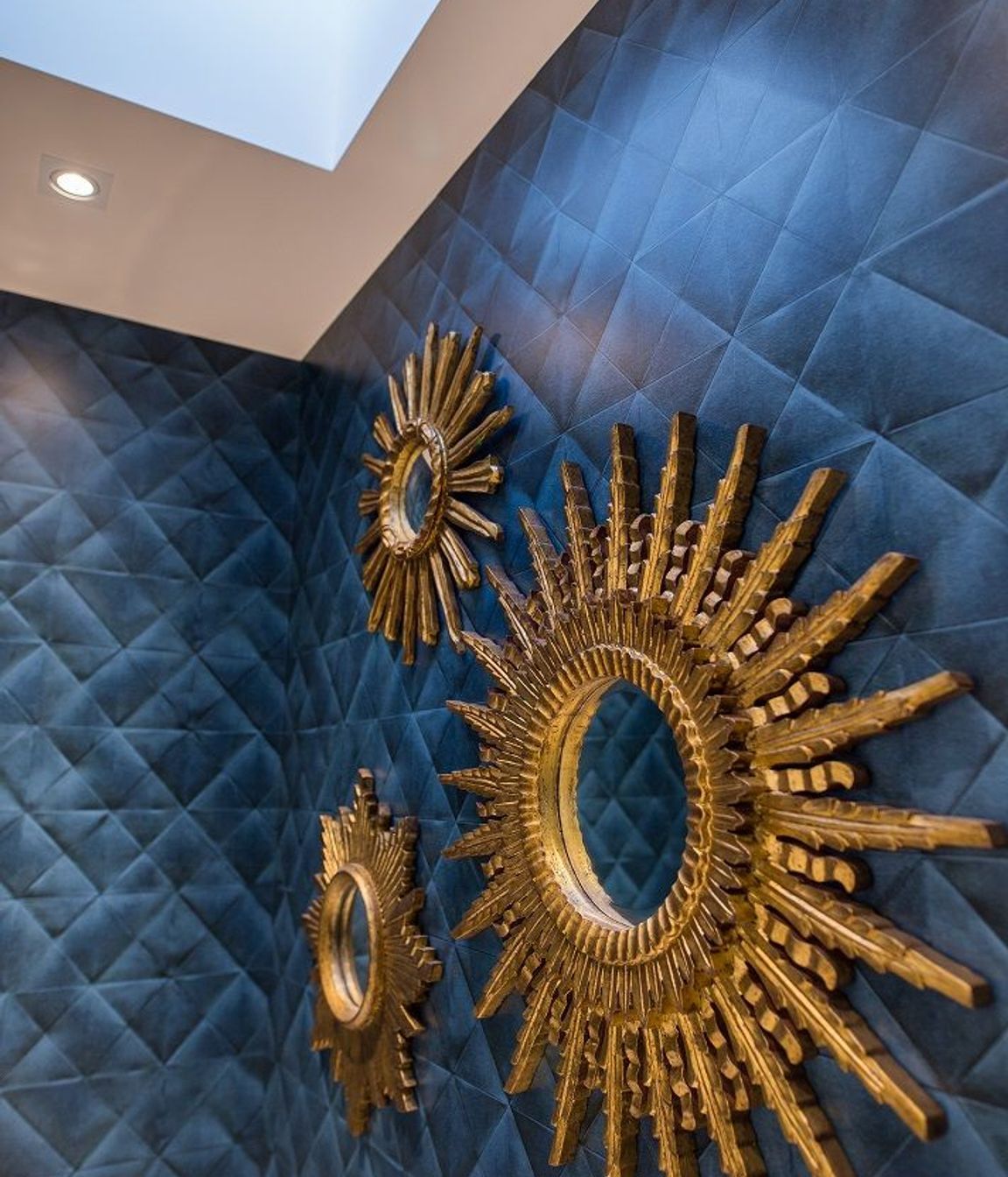 A trio of ornate gilt mirrors bring a sense of drama to the powder room.