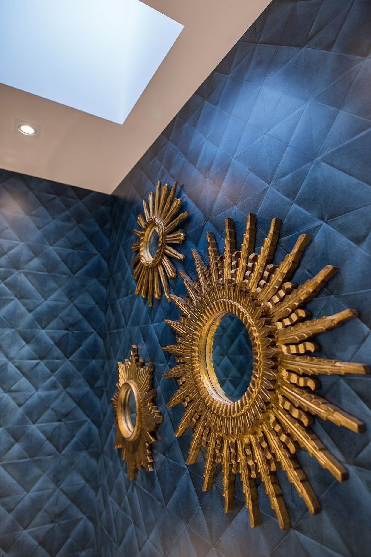 A trio of ornate gilt mirrors bring a sense of drama to the powder room.