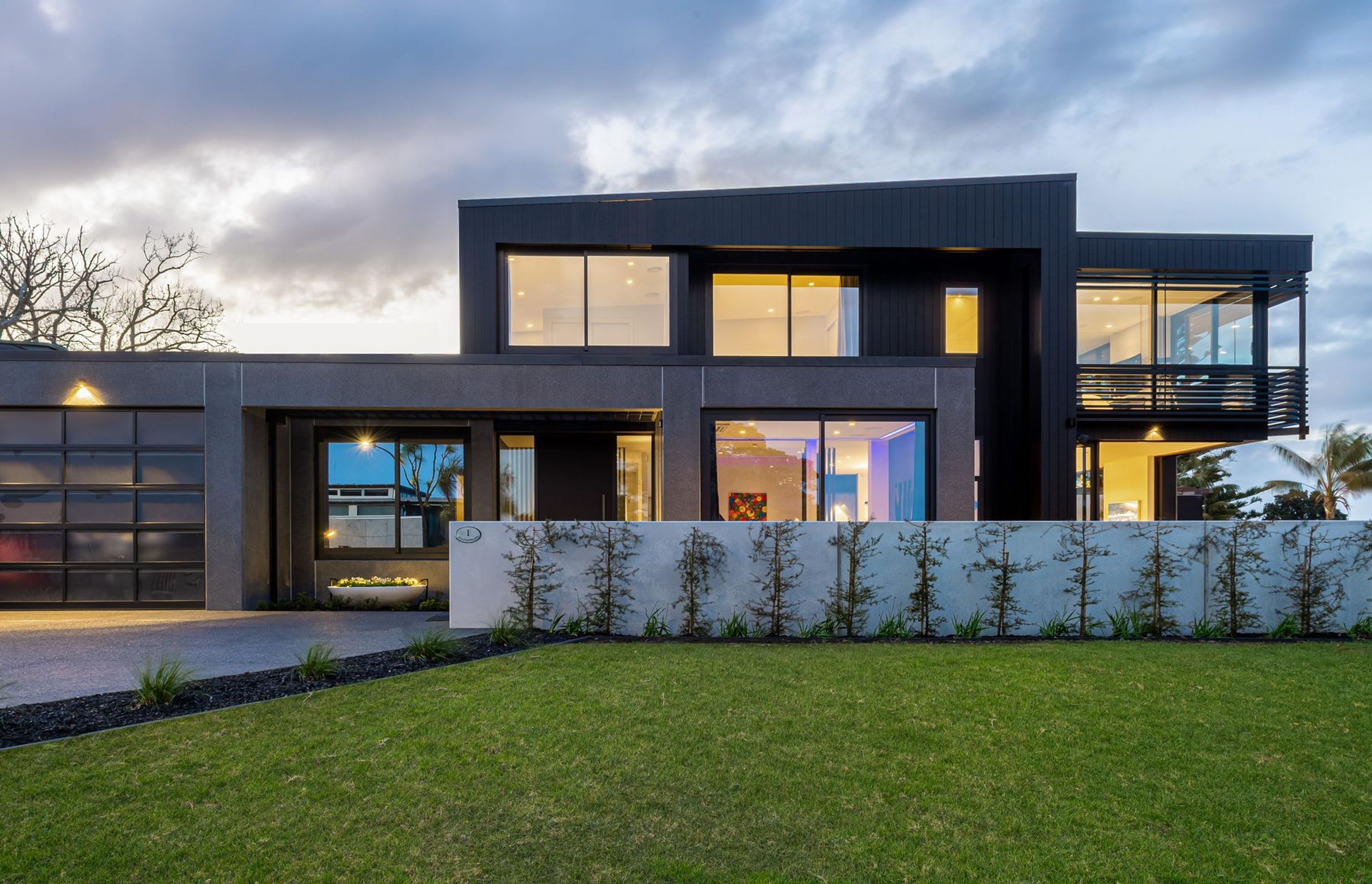 The plan reads as three boxes—a solid, polished black concrete ‘pillbox’ base; a two-storey black vertical timber central element; and, a floating lightweight glass ‘conservatory’ that houses the master suite.