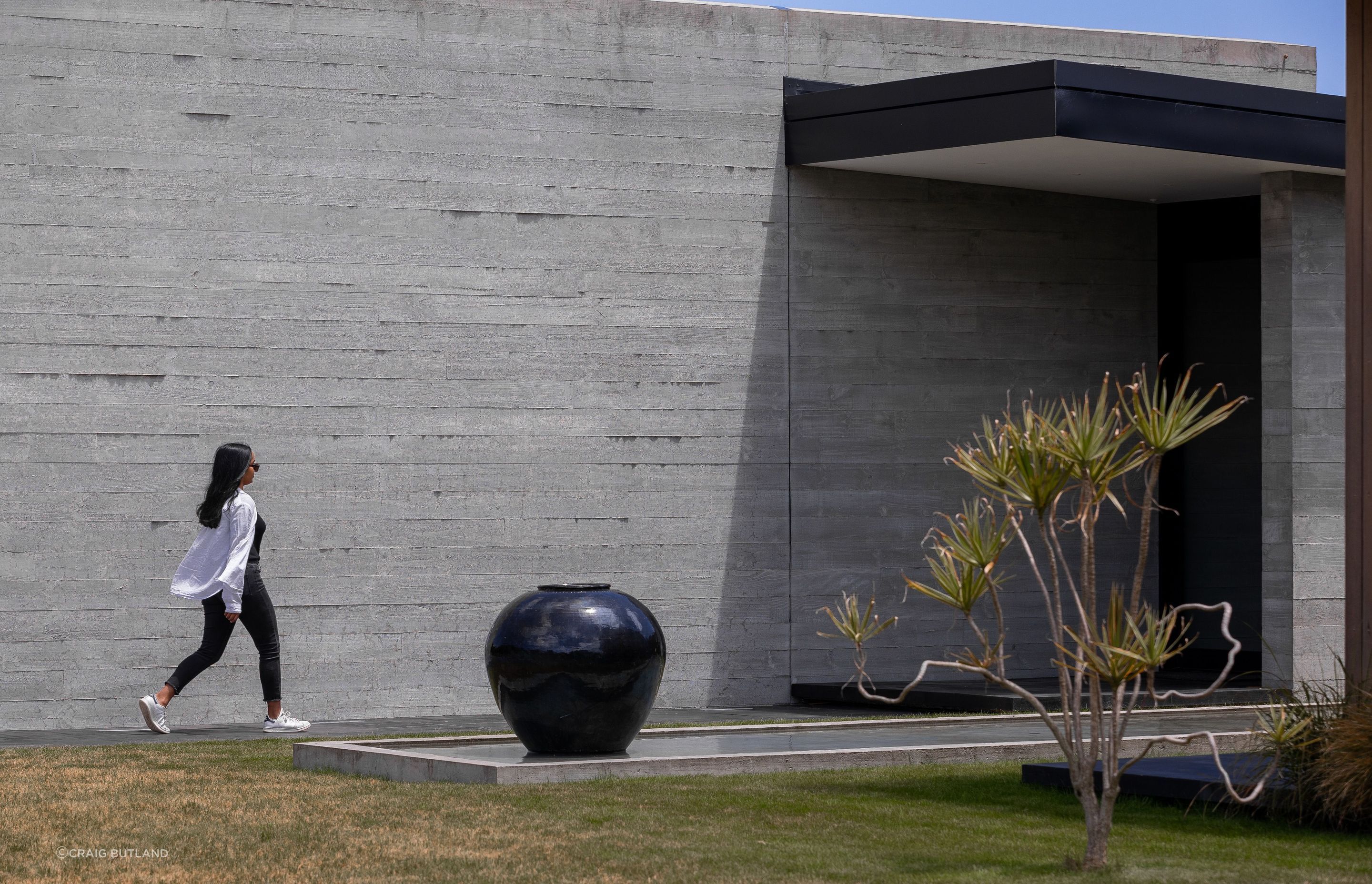 Insitu-concrete walls lead past the reflection pool to the entry.