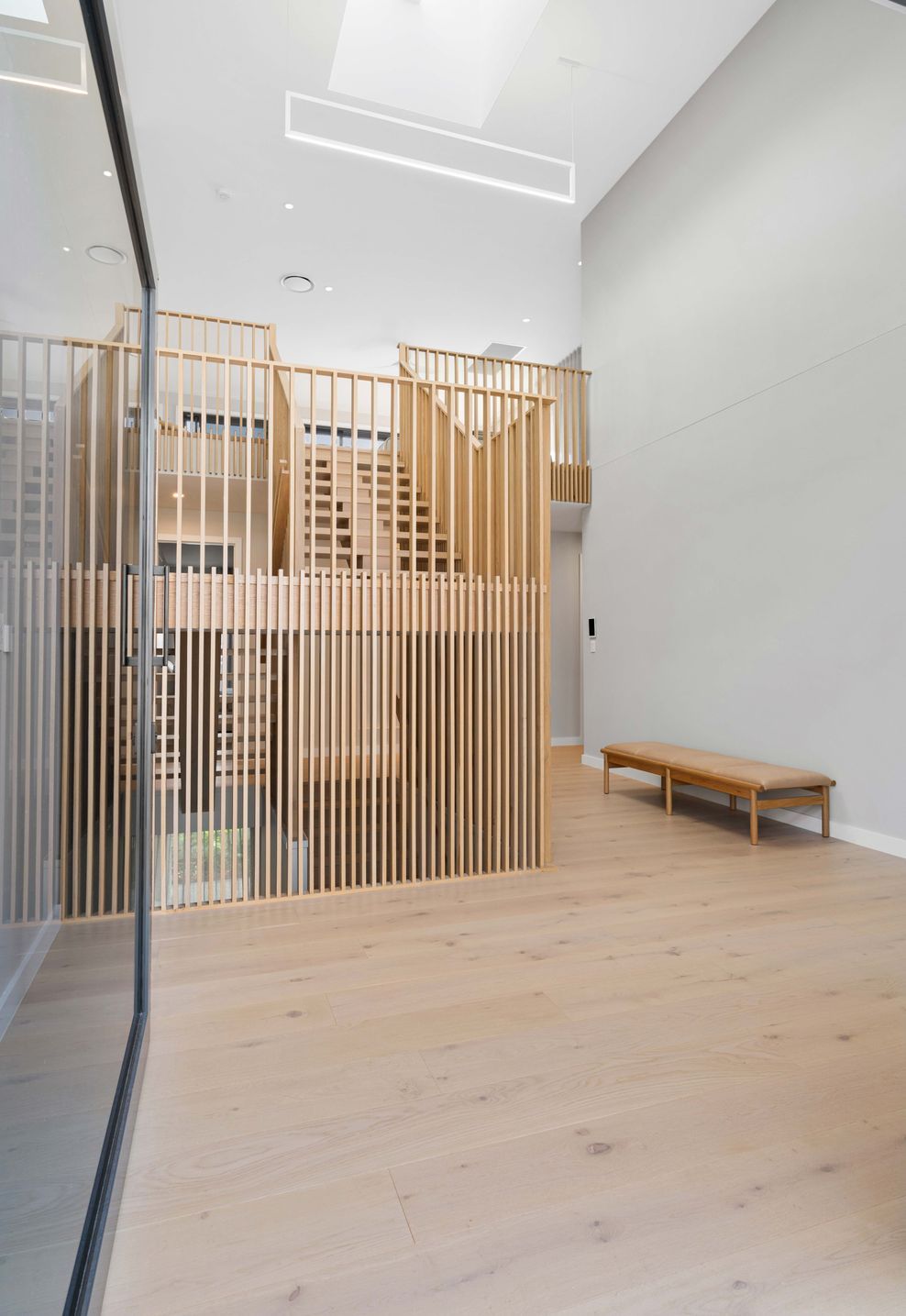 A timber-slatted wall and skylight give the entry hall its double-height presence.