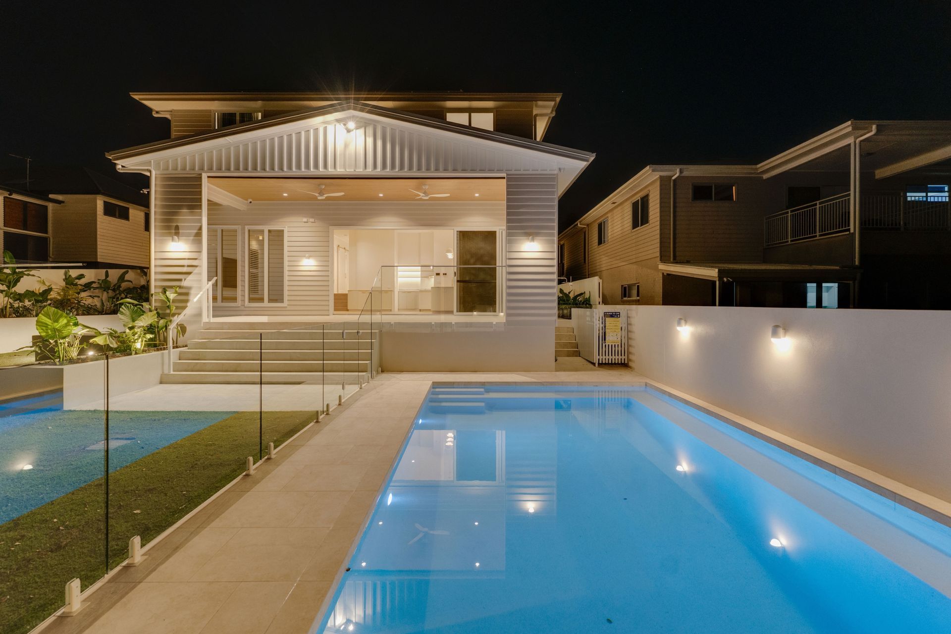 At dusk the home opens fully to the pool, alfresco and lawn beyond.