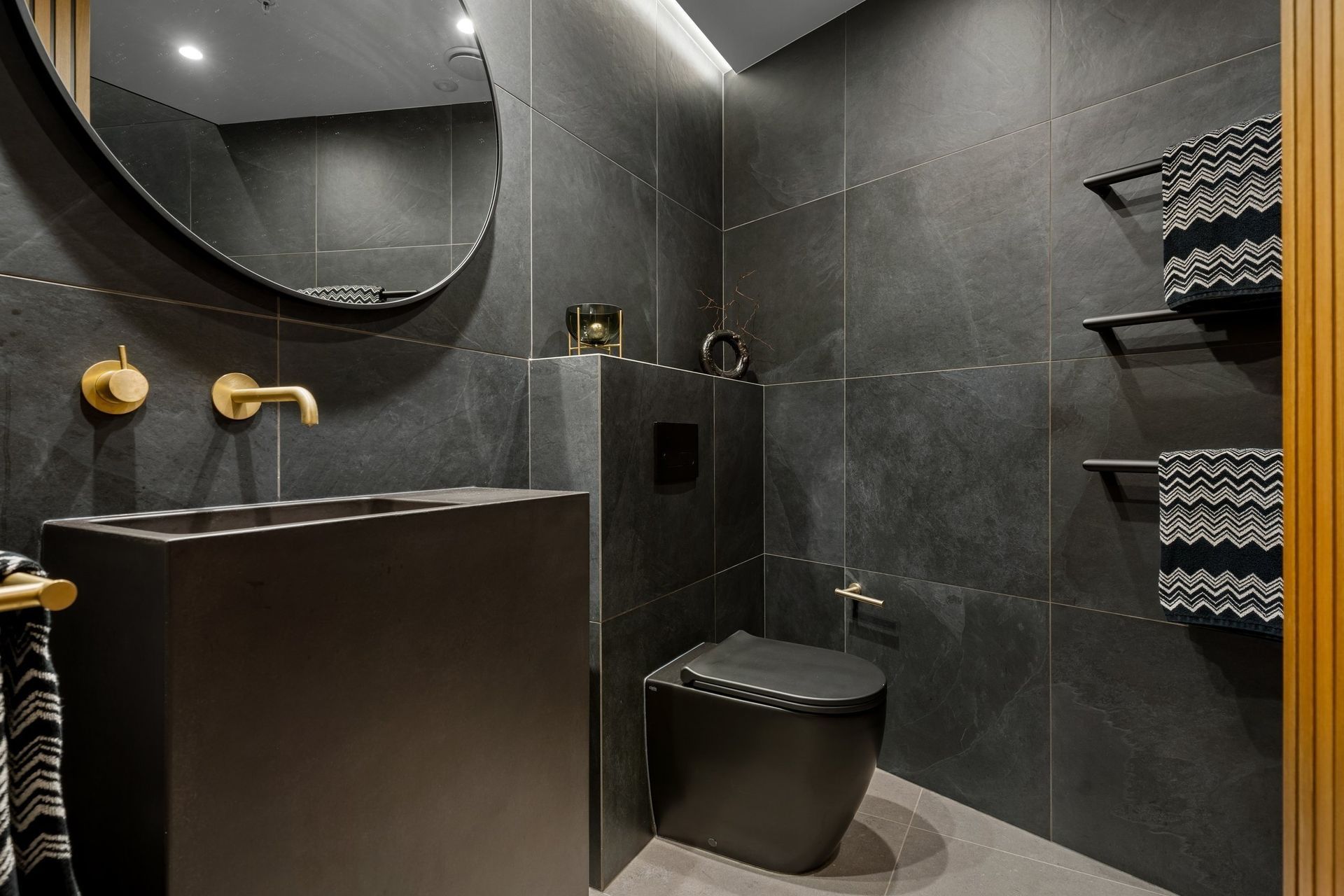 A sophisticated palette highlights the elegant aged brass Progetto tapware paired with a sleek Concrete Nation vanity, creating a stylish and cohesive aesthetic.