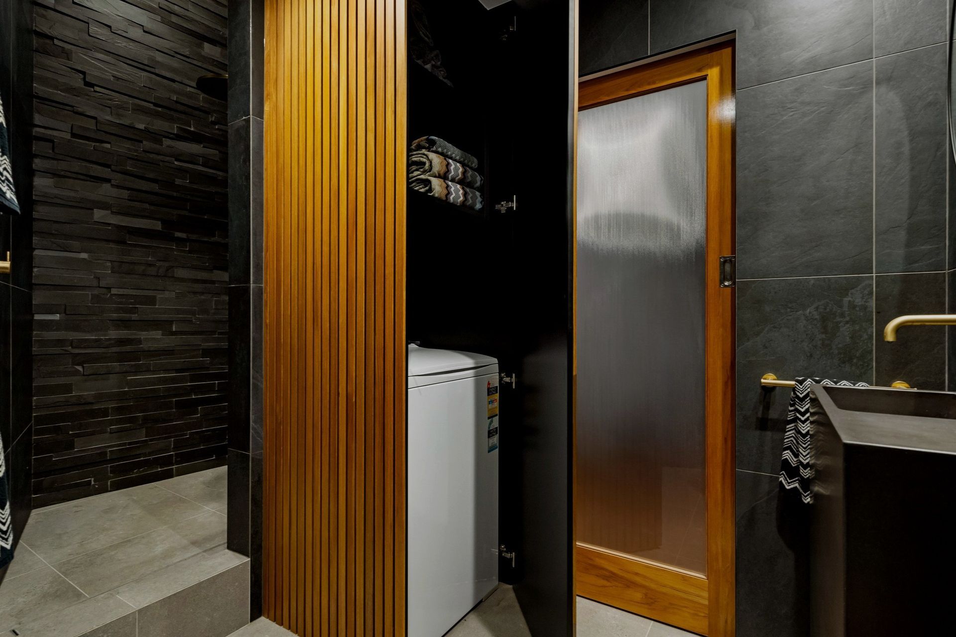 The wood-paneled cupboard discreetly hides a secret laundry space, complete with additional storage for an organized and stylish solution.