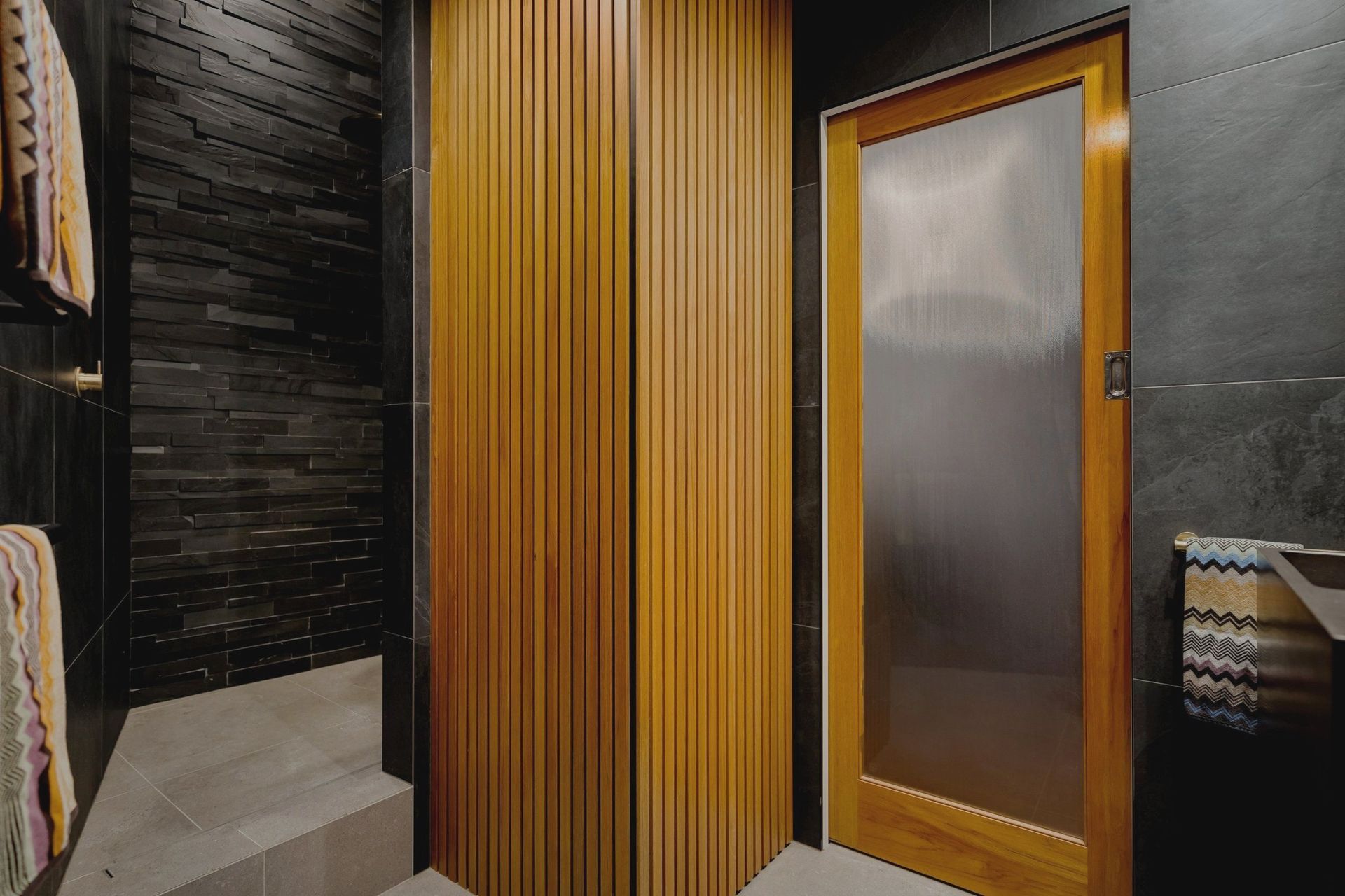 The warm-toned Rimu wood paneling elegantly conceals a hidden laundry cupboard, while a custom sliding door has been crafted to complement the heritage character of the building and coordinate seamlessly with the other apartment doors.